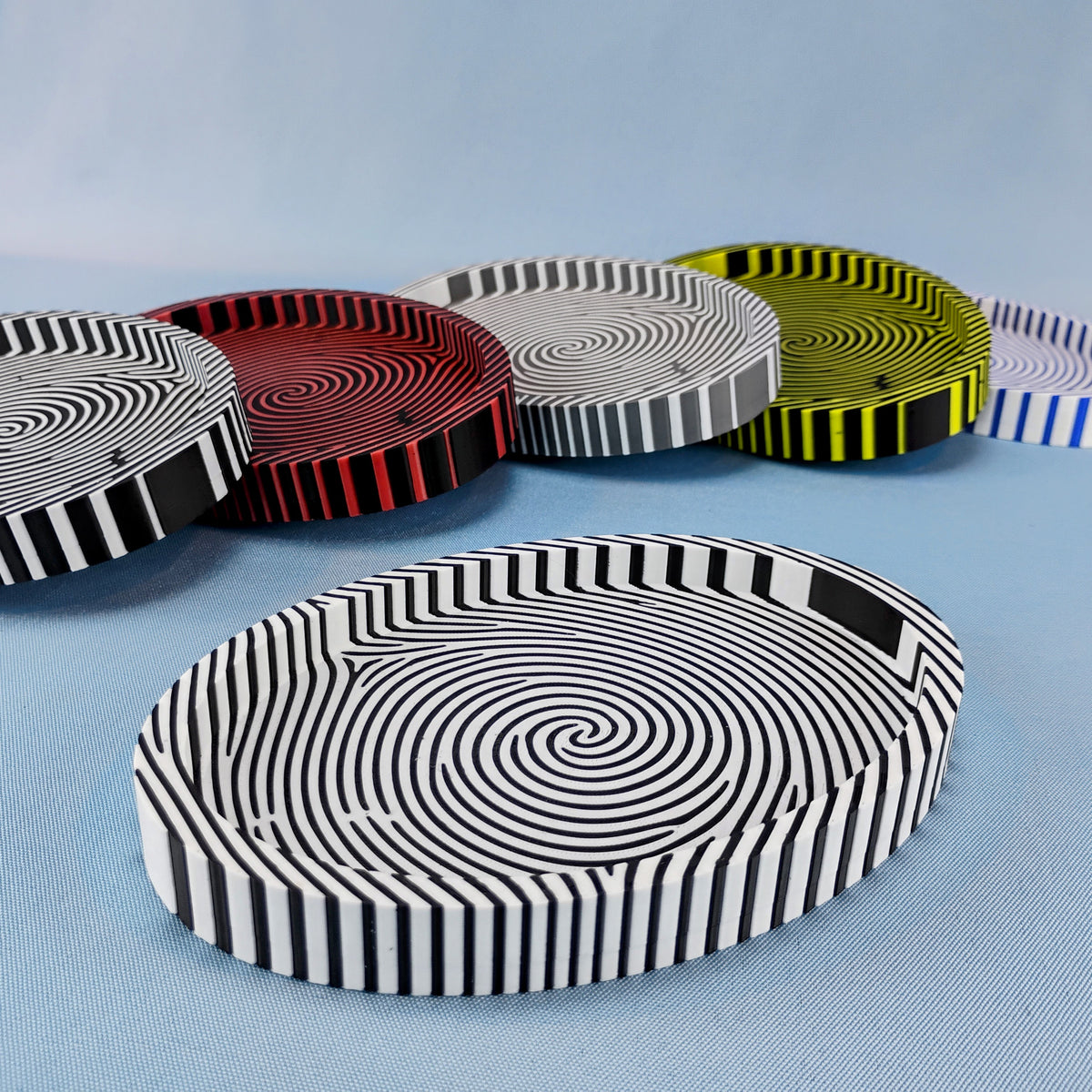 Fingerprint catchall trays in black and white, red and black, gray and white, yellow and black, and blue and white color combinations.