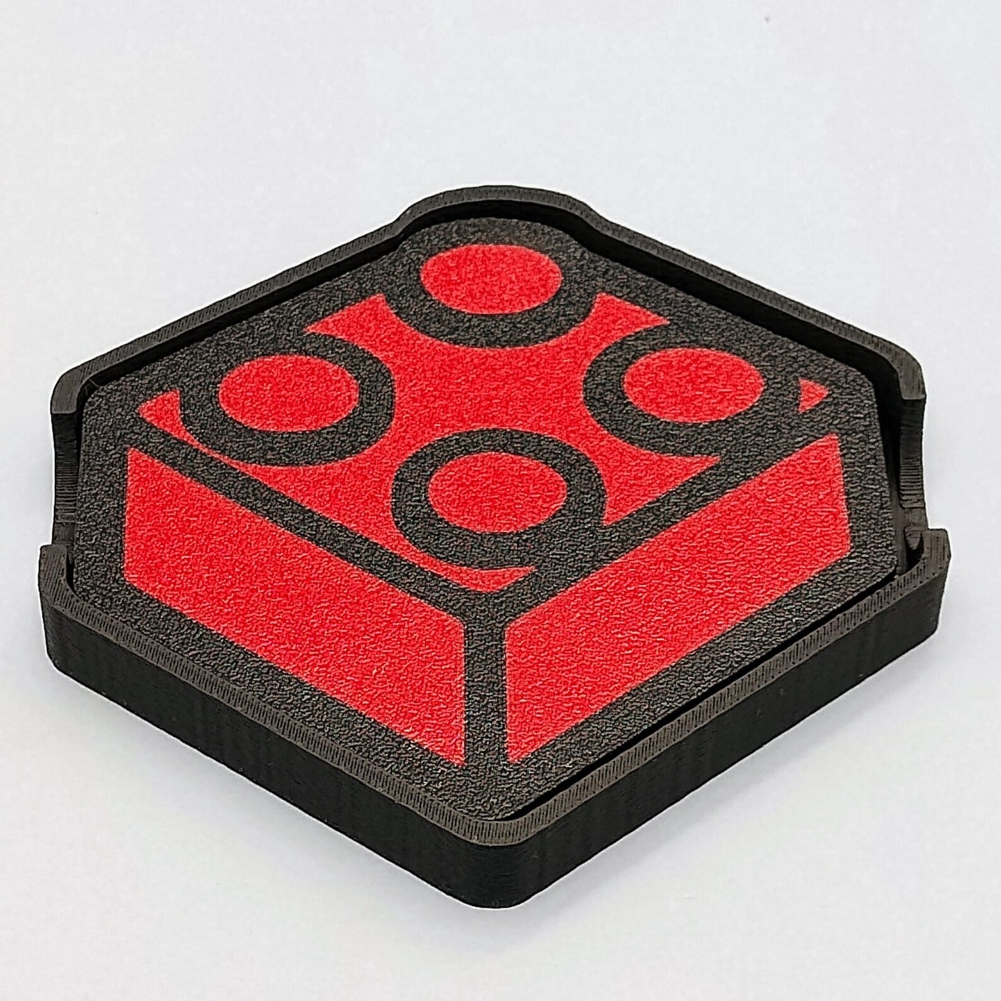 Red brick-inspired coaster sitting inside a matching black holder