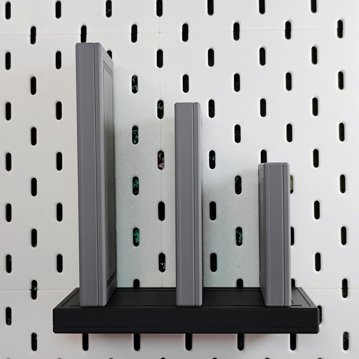 Gray and black floating shelf for SKADIS pegboard shown with upright books