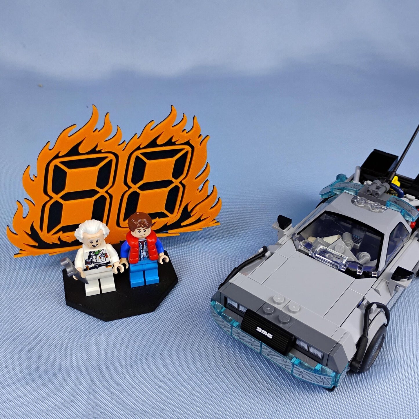 Back to the Future minifigure display with 88 MPH flame backdrop, two figures, and DeLorean time machine build on a blue background.