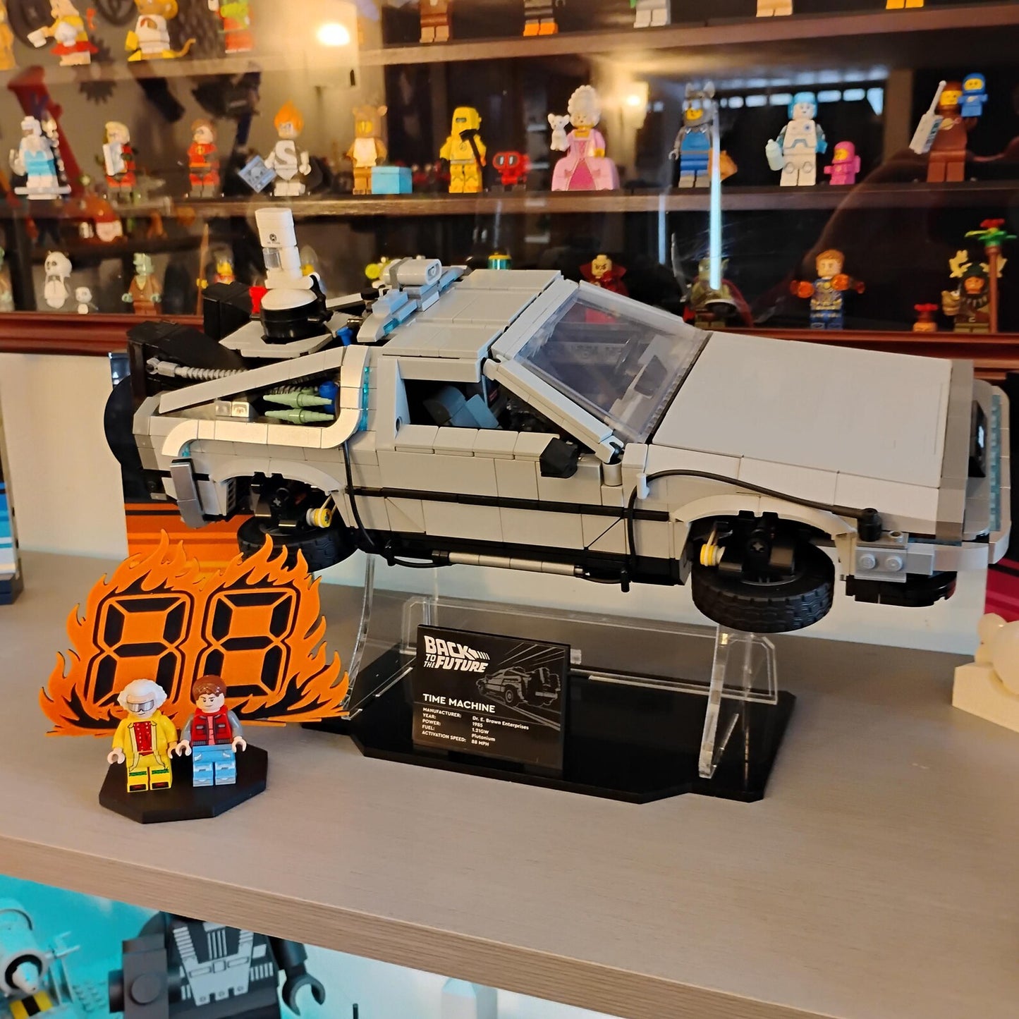Back to the Future minifigure display shown on a collector shelf beside a DeLorean time machine build and other display pieces.