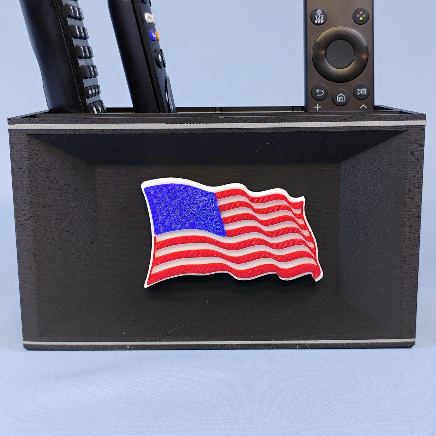 Black American flag desk organizer holding TV remotes with raised red white and blue flag detail