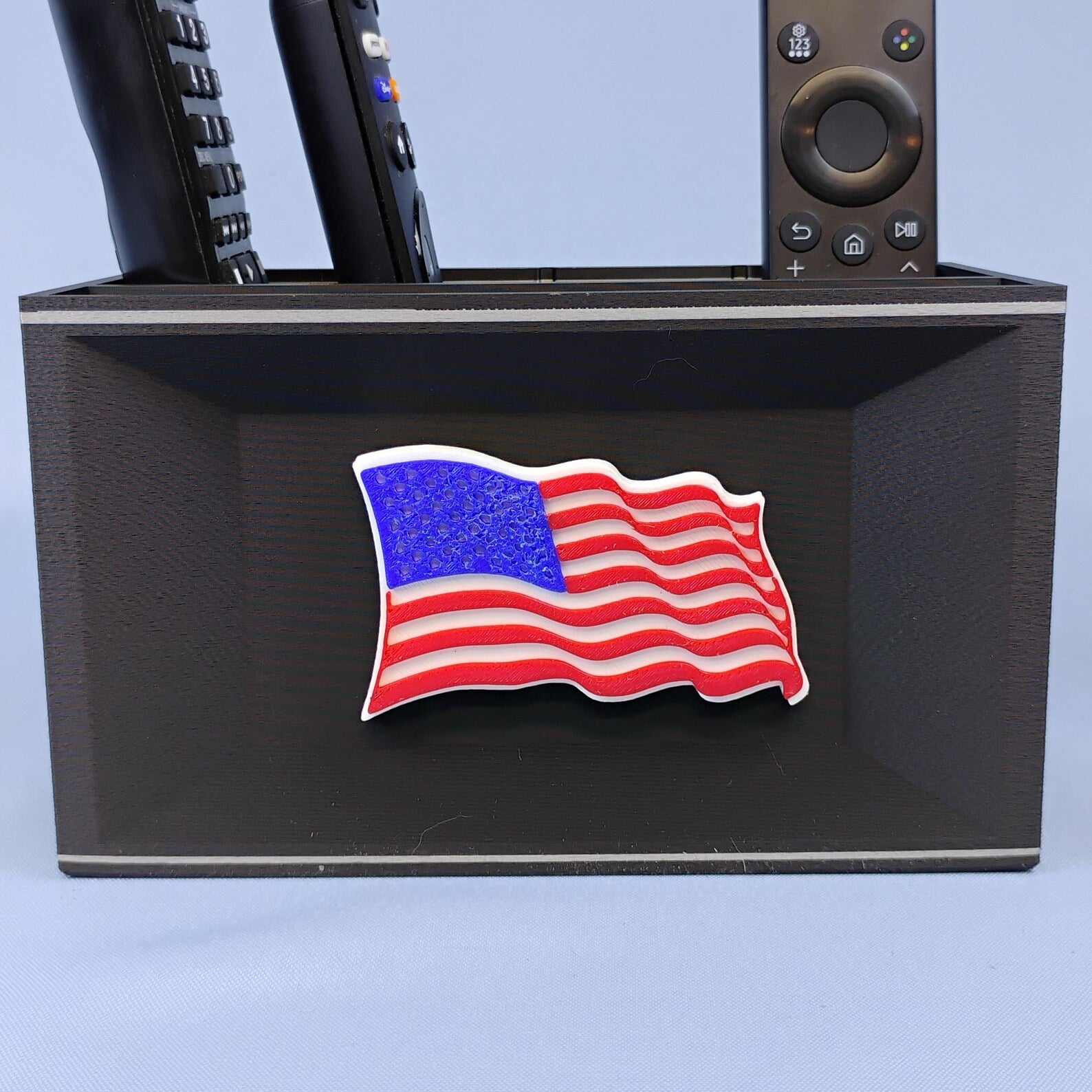 Black American flag desk organizer holding TV remotes with raised red white and blue flag detail