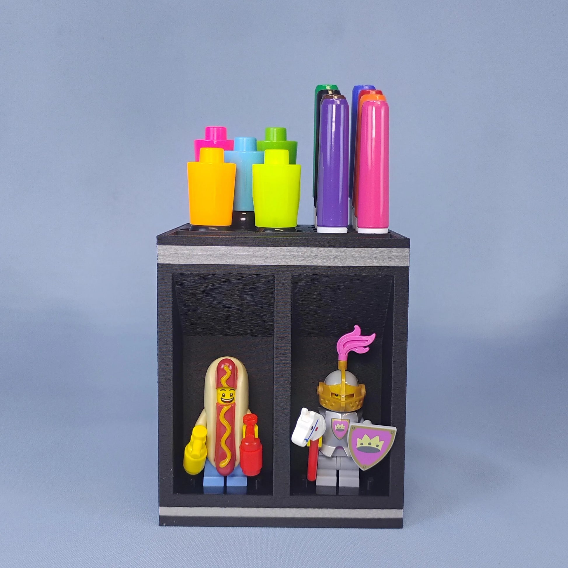 Front view of a black dry erase marker holder filled with colorful Expo-style markers and two LEGO® minifigures in separate display bays.
