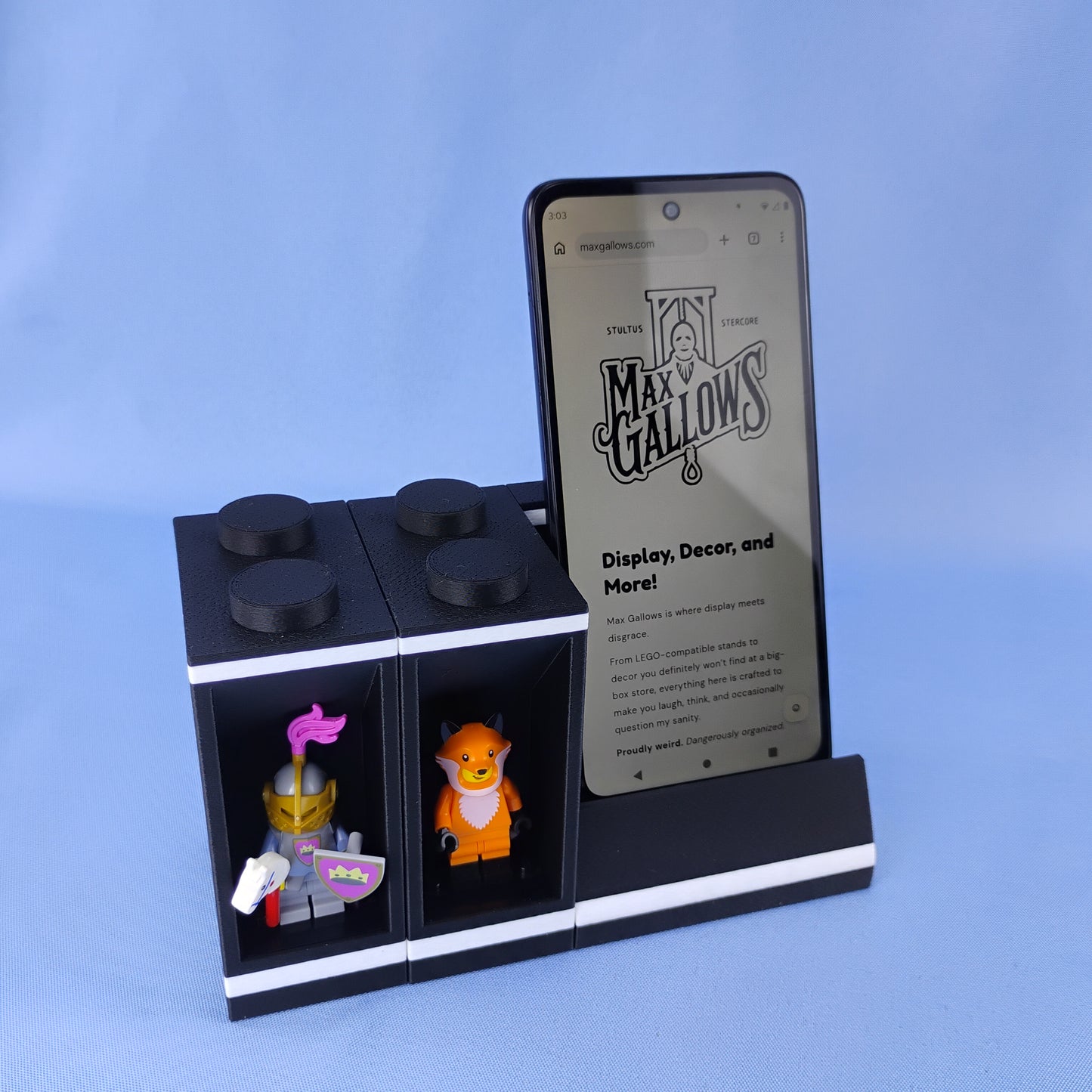 Black LEGO® minifigure display module connected beside a smartphone stand for a compact desk display setup.