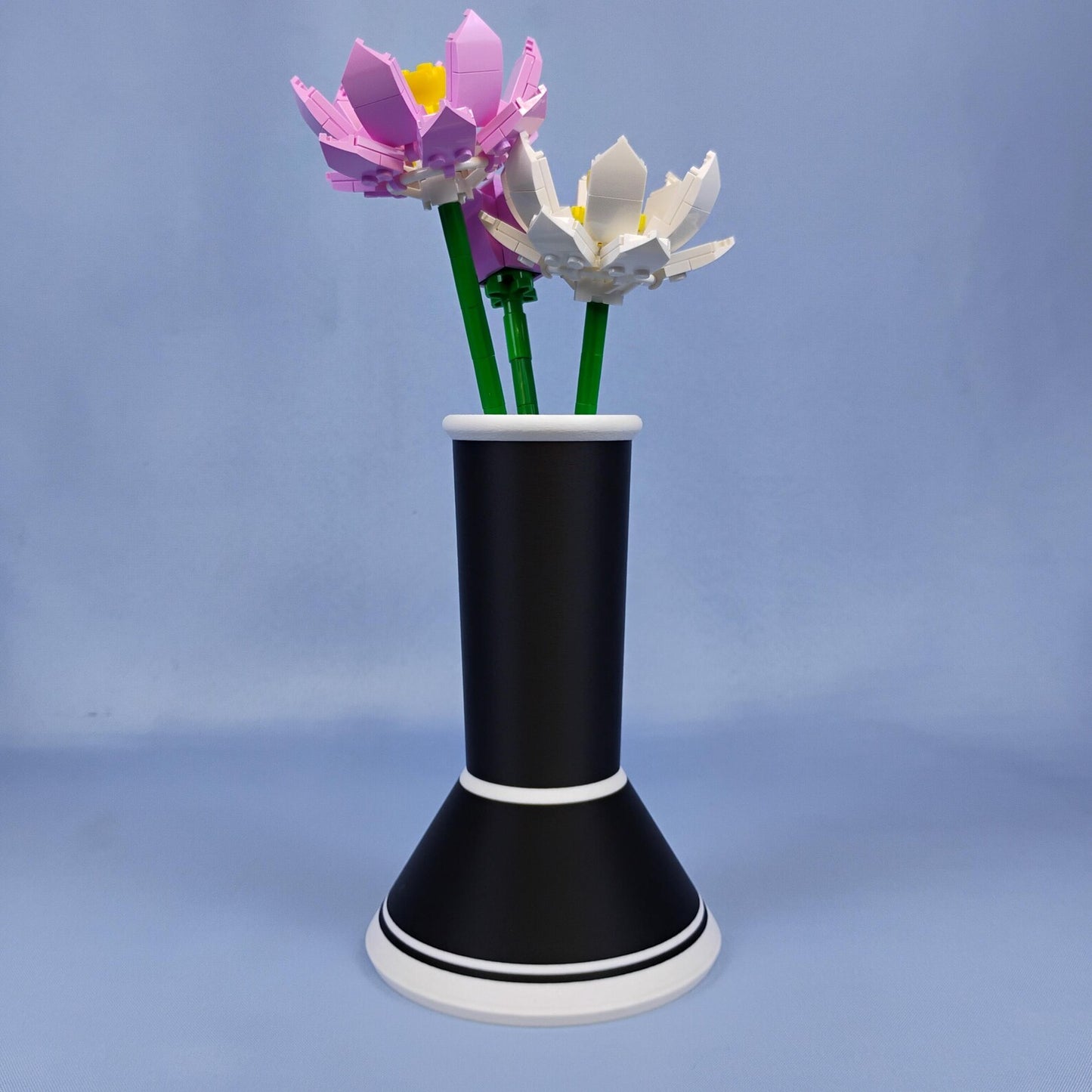 Black minimalist vase holding LEGO® lotus flowers with a removable stem insert