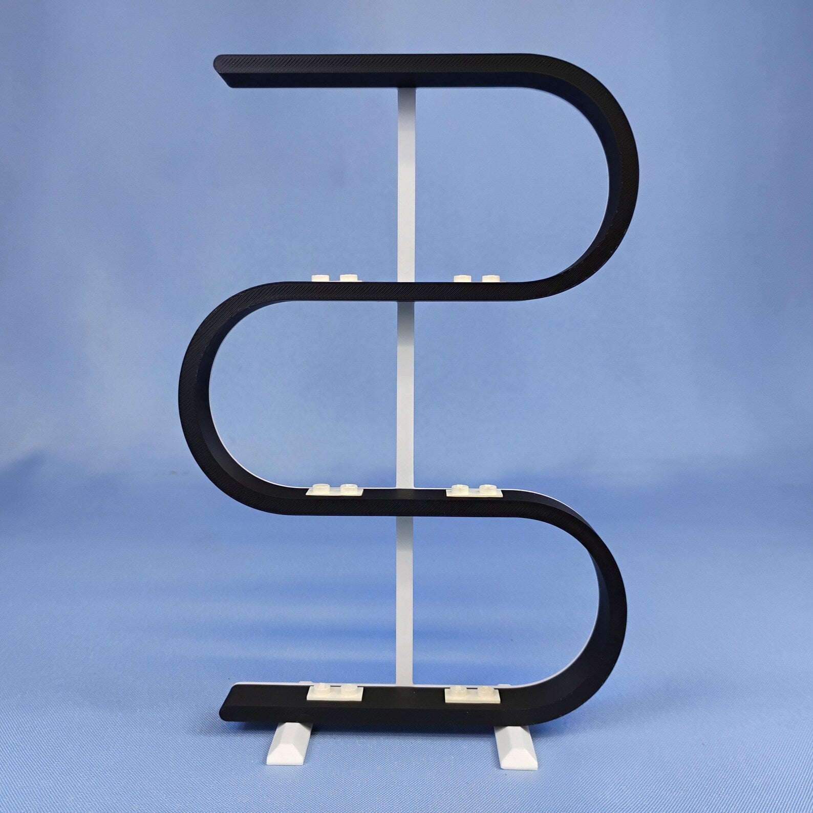Empty black squiggle display stand for LEGO® minifigures on a blue background