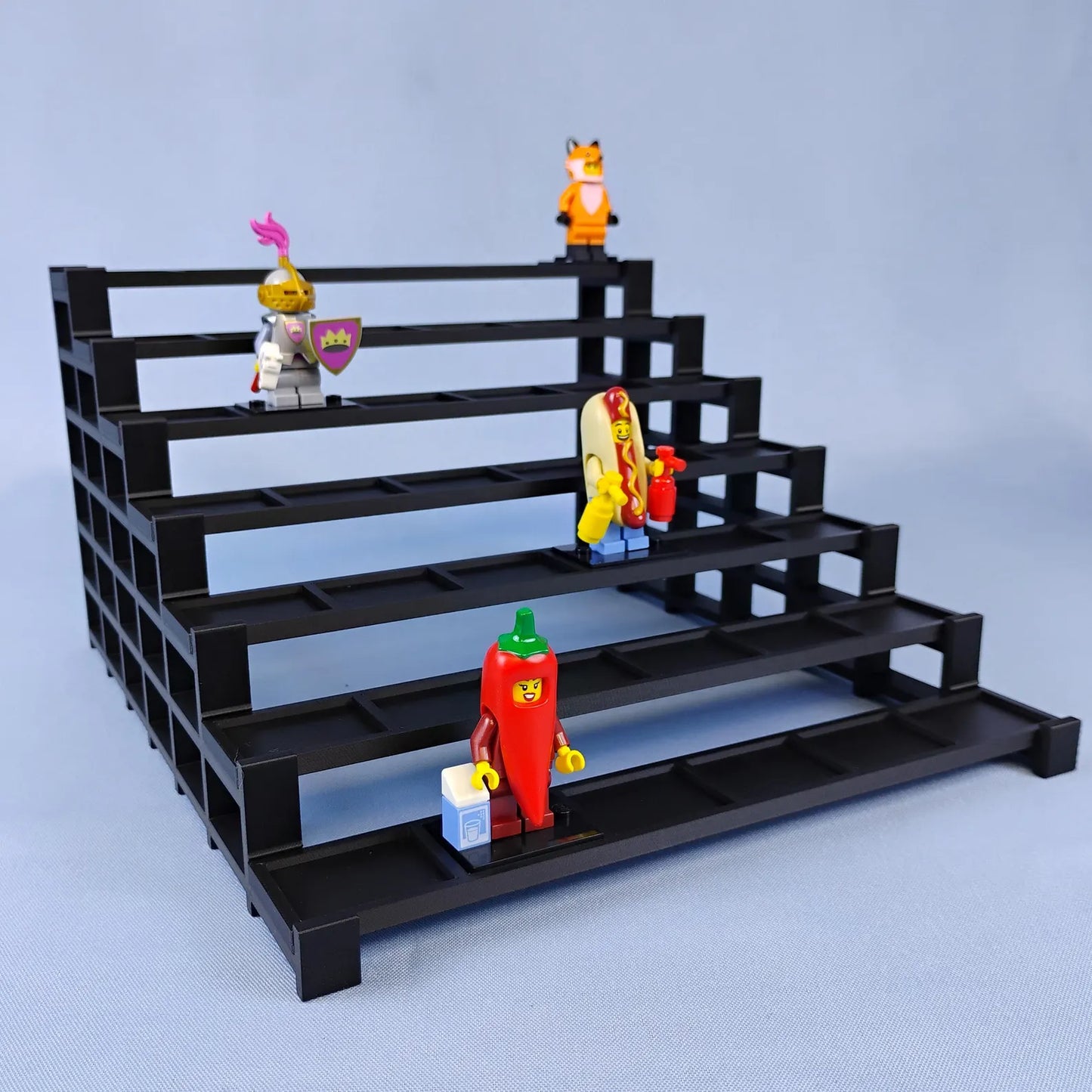 Black tiered display stand for LEGO® minifigures with several figures arranged across the stepped rows.