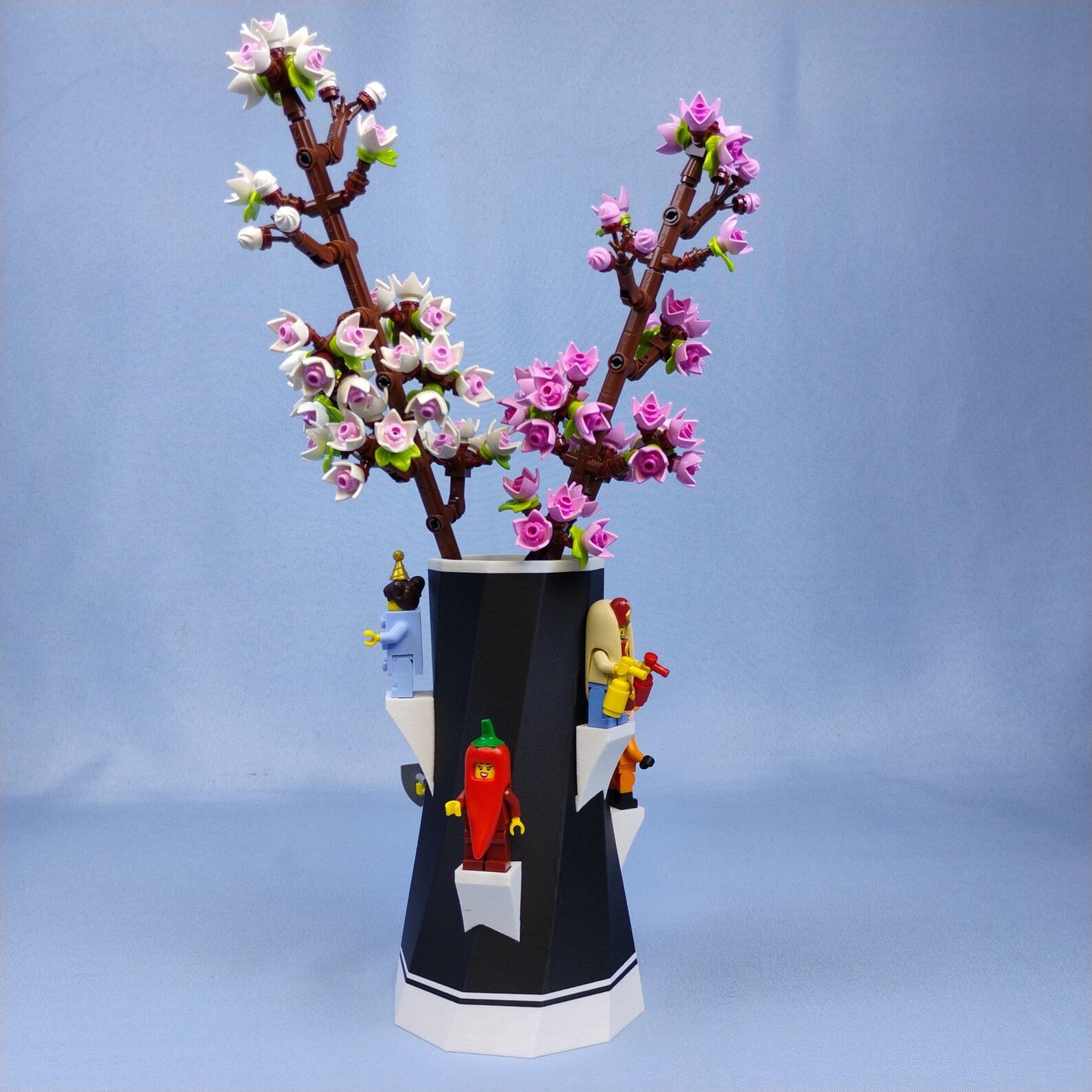 Black vase holding LEGO® cherry blossoms with minifigures displayed around the base
