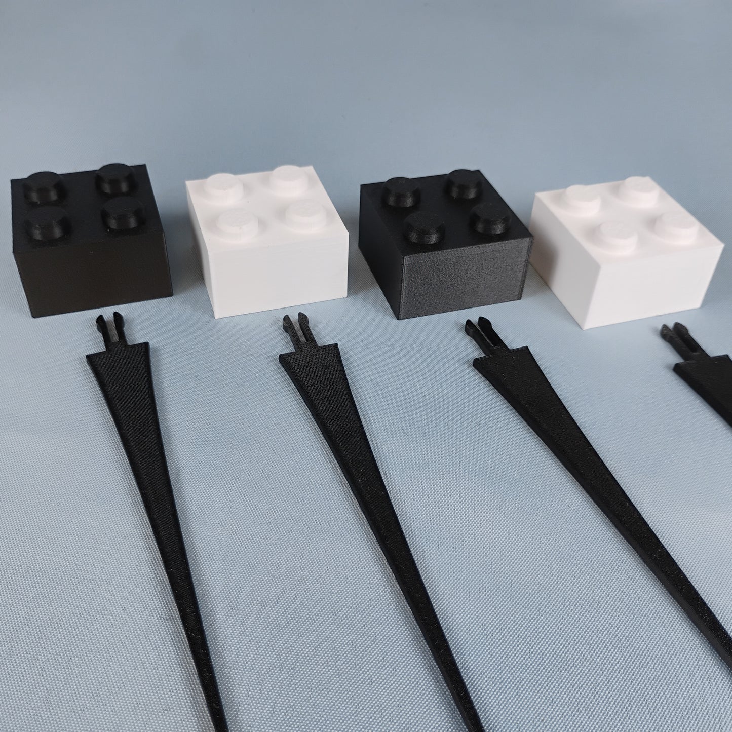 Set of four black and white building brick plant stakes displayed together on a neutral background.