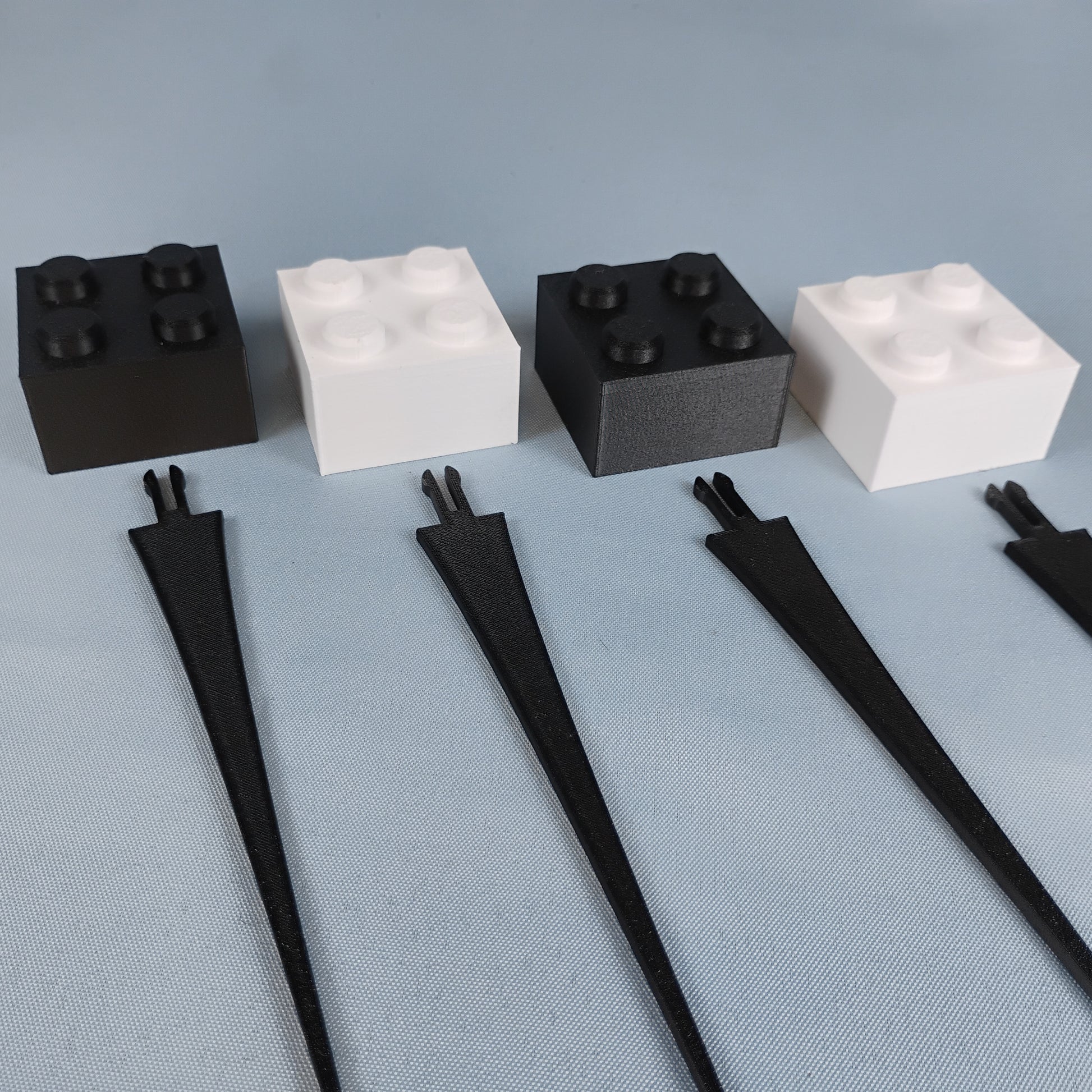 Set of four black and white building brick plant stakes displayed together on a neutral background.