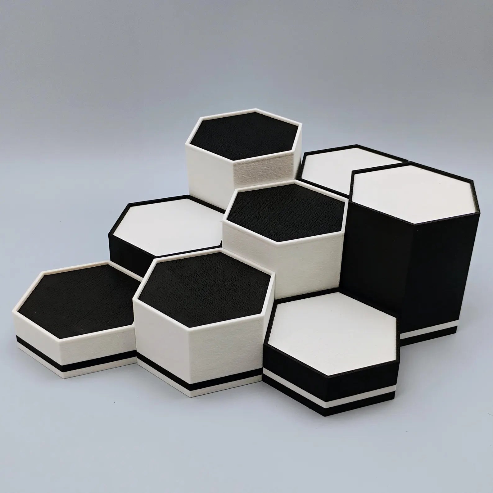 Empty black and white hex display stands arranged in a tiered set with multiple heights for collectibles and figures.