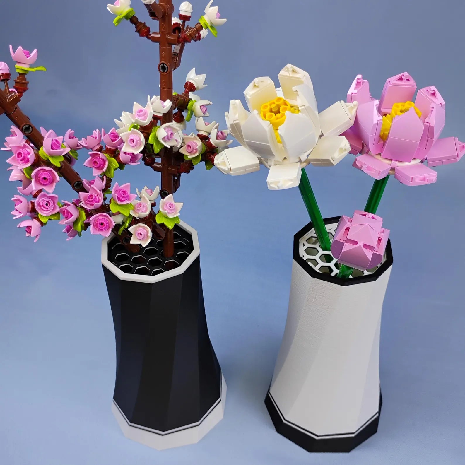 Black and white LEGO® Botanical flower vases displayed side by side with cherry blossoms, lotus flowers, and other small flower stems.