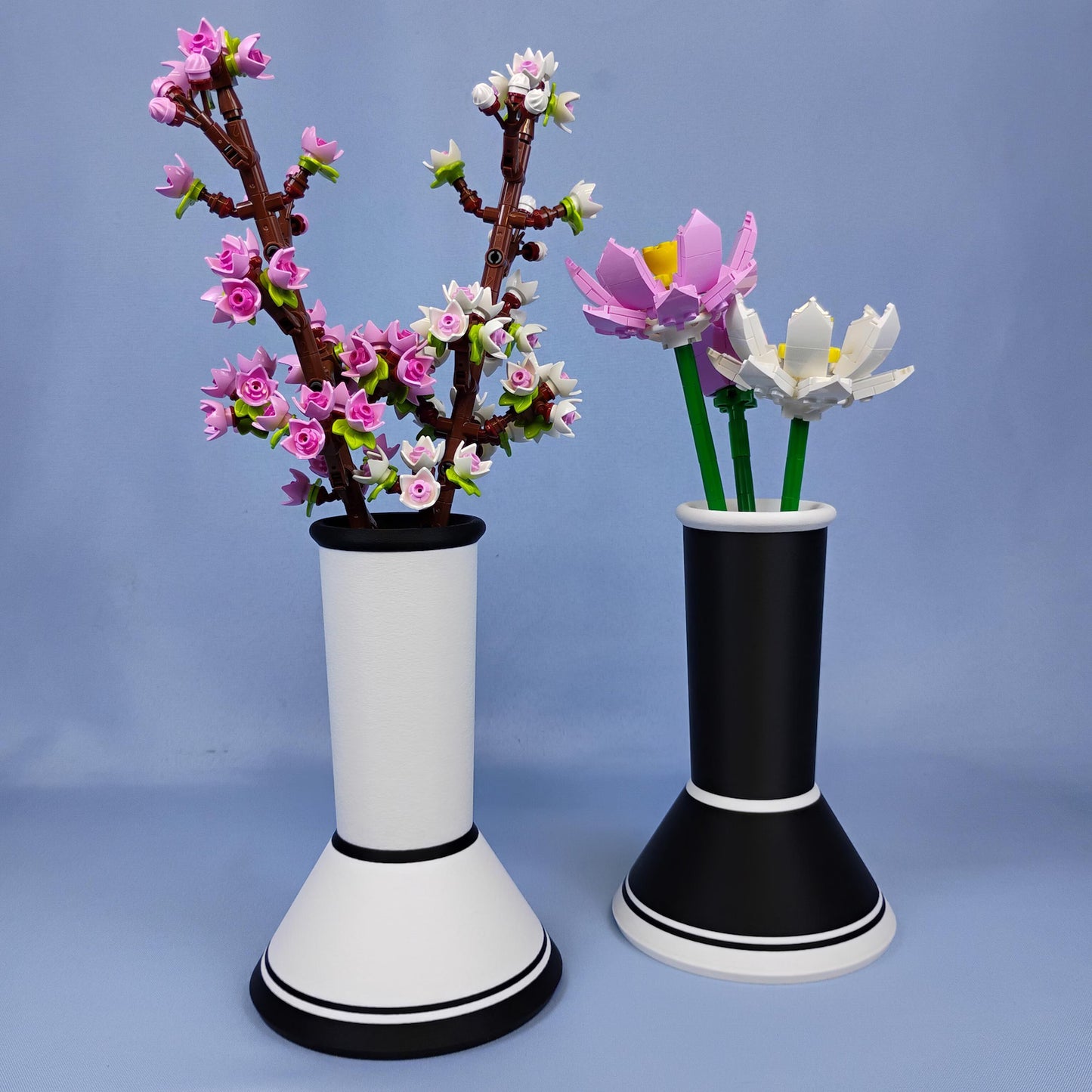 Black and white minimalist vases displaying LEGO® botanical flowers on a blue background