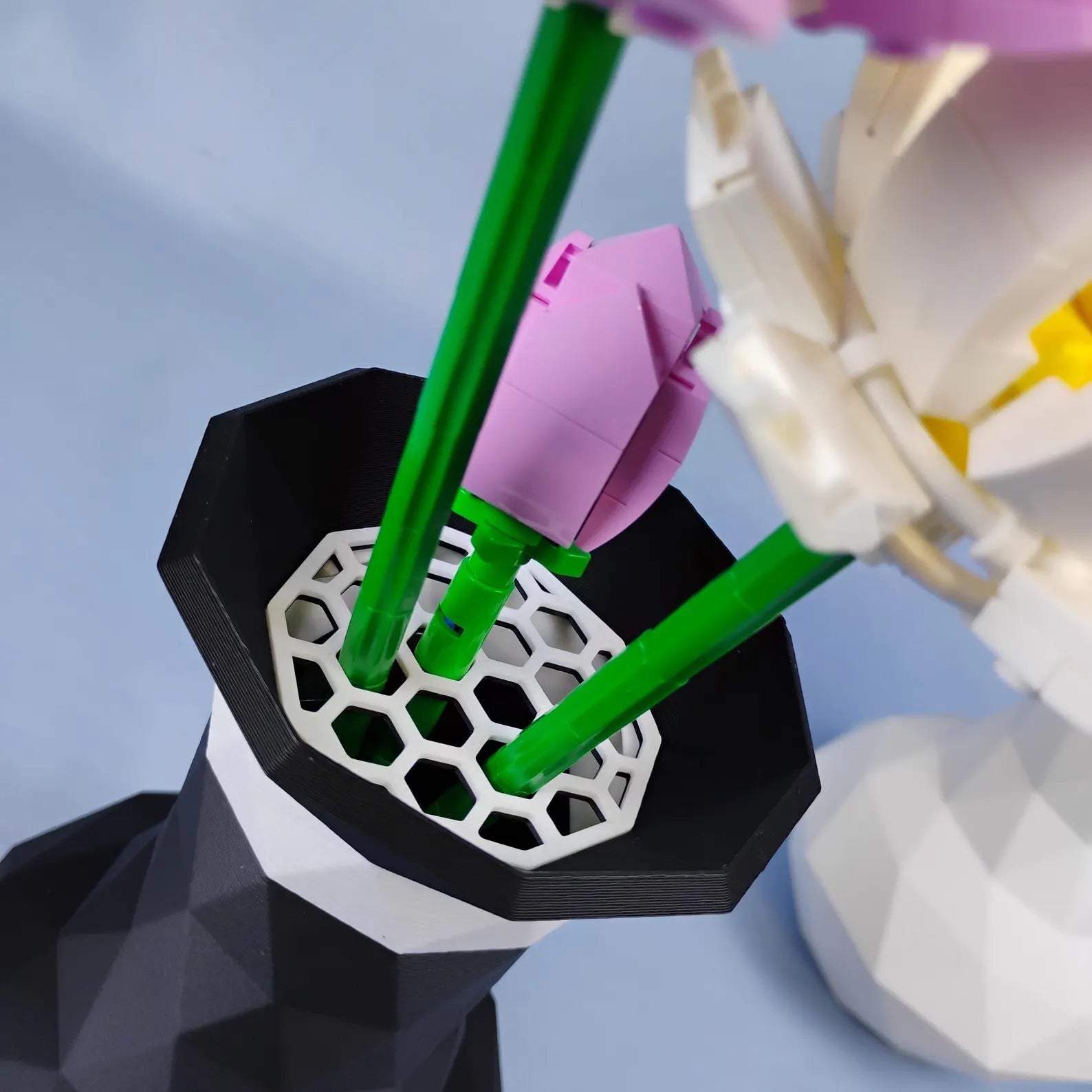 Close-up of LEGO® botanical stems placed into the removable grid insert of a geometric vase