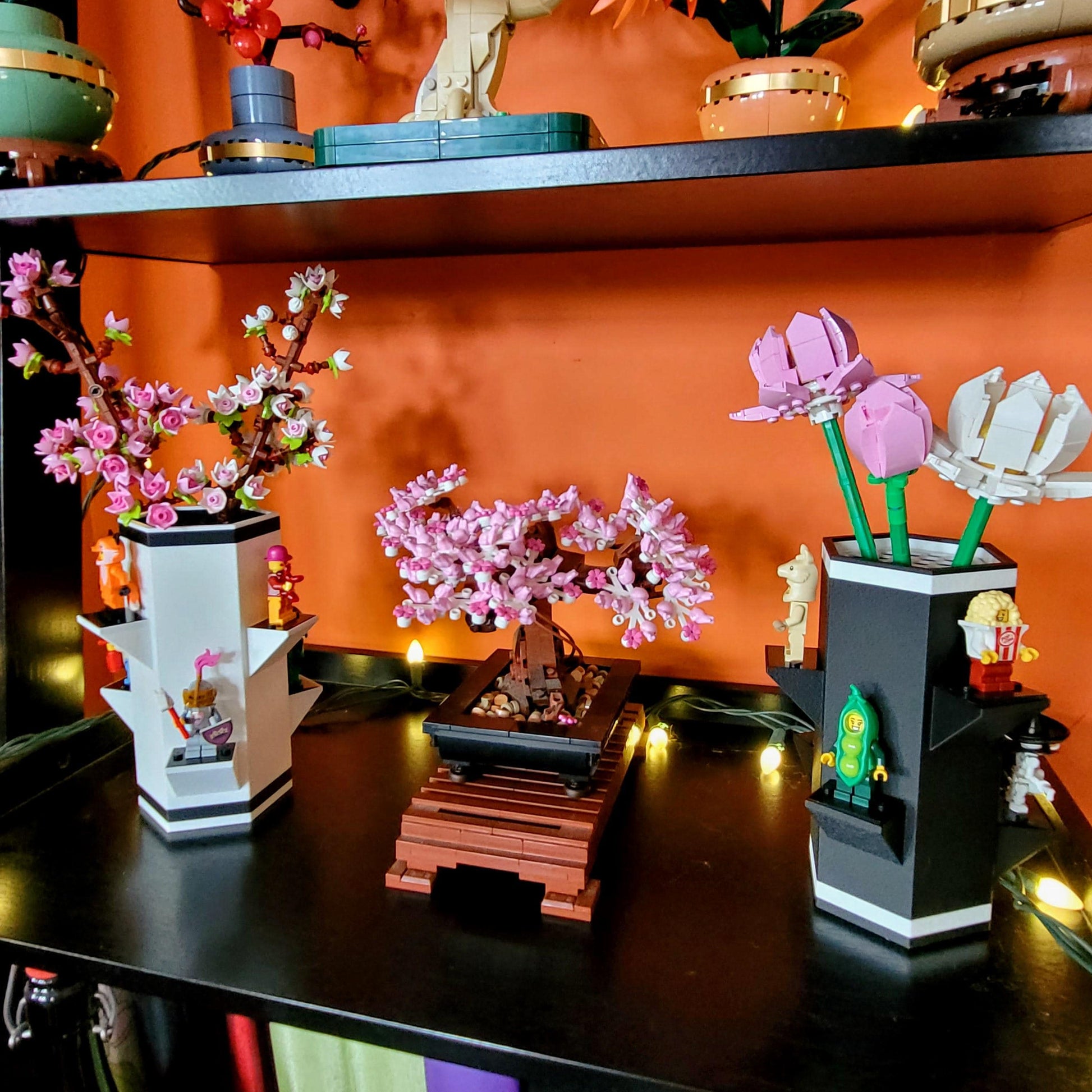 Lego Botanical sets in vases with minifigures on a shelf with an orange background