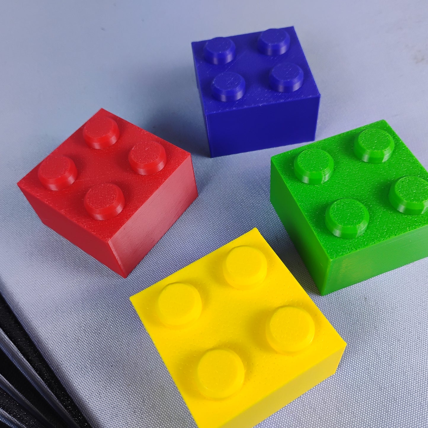 Close-up of red, blue, green and yellow building brick toppers used with removable plant stakes.