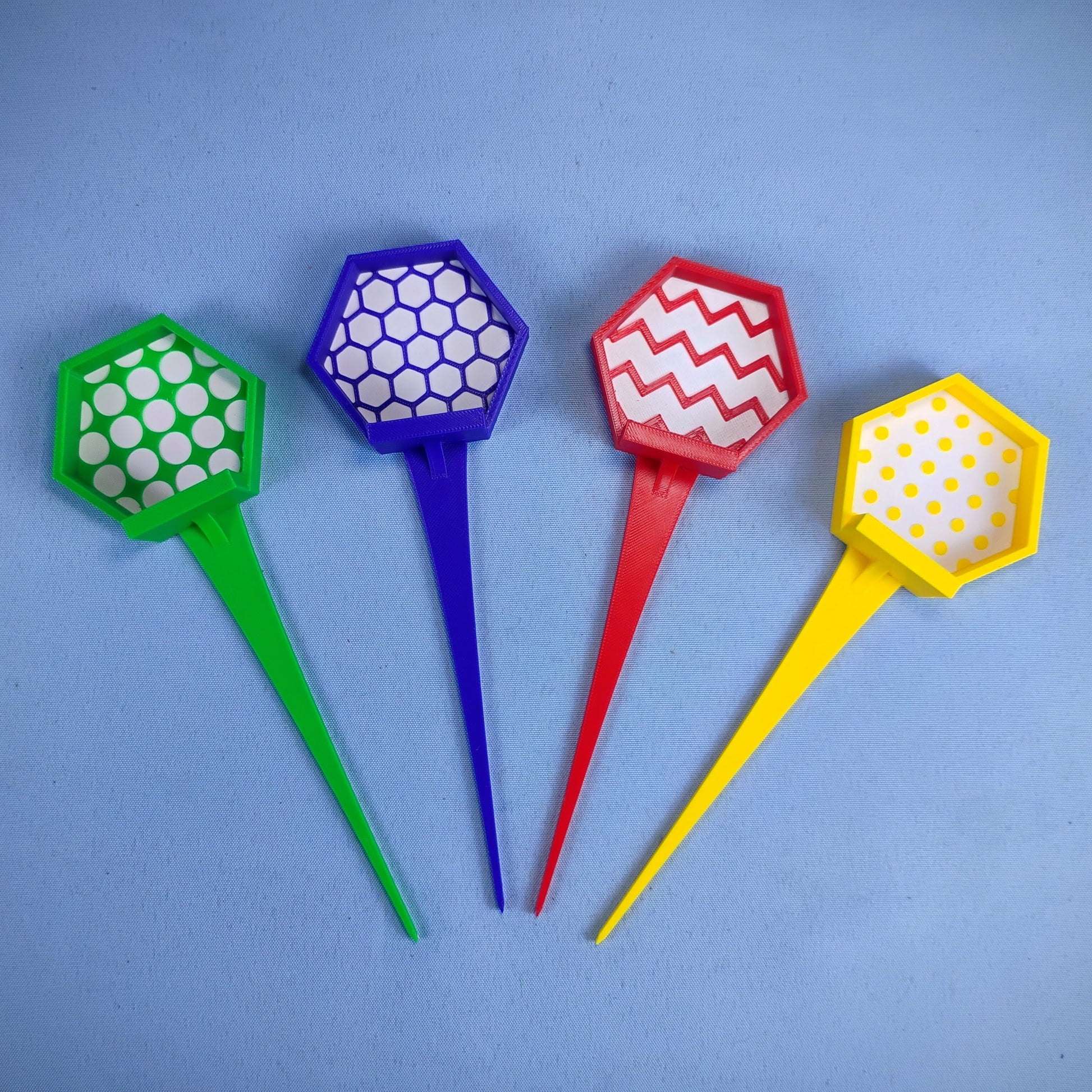Set of four full-length colorful LEGO® minifigure plant stakes in green, blue, red and yellow with patterned display tops.