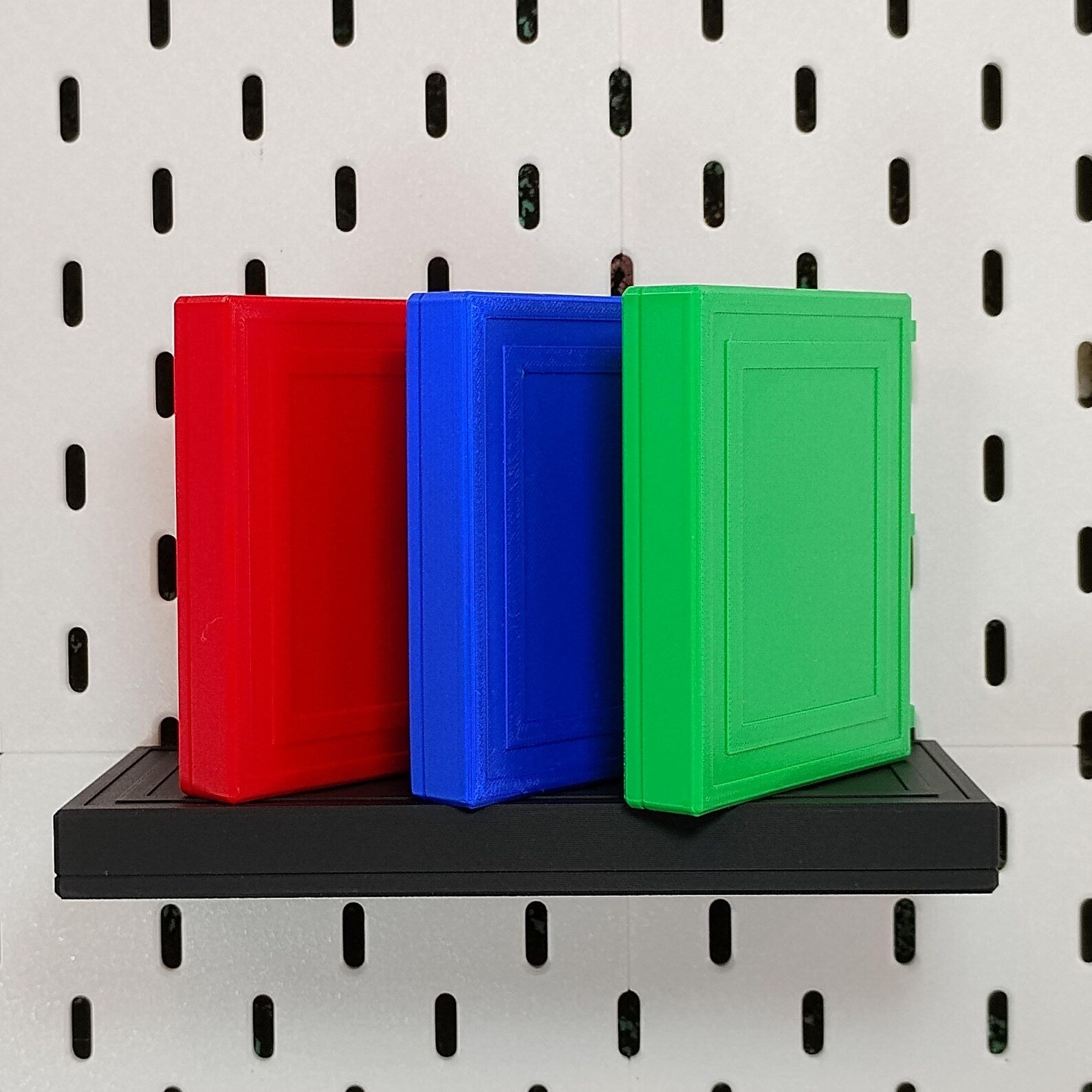 Red, blue, and green floating shelves installed on an IKEA SKADIS pegboard