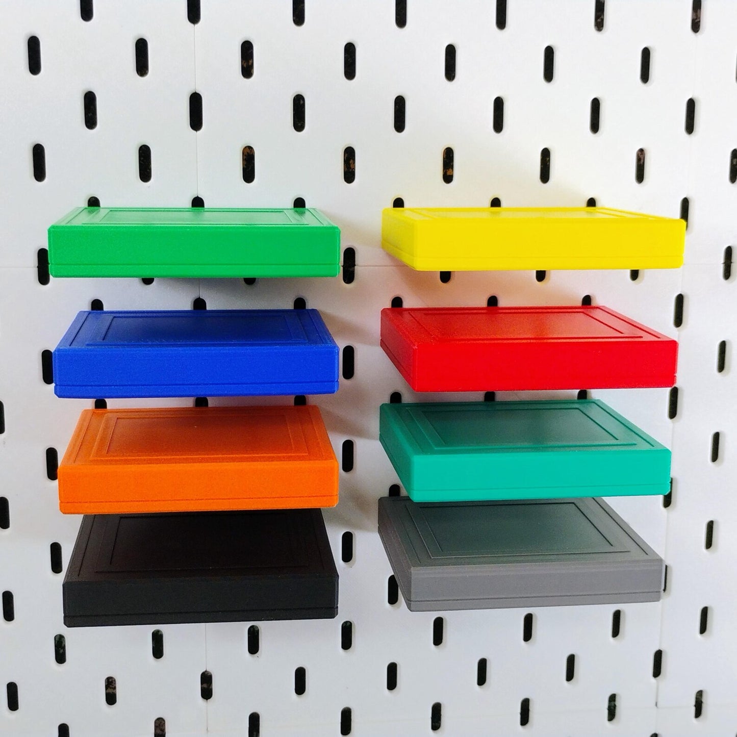 Stack of colorful SKADIS floating shelves in green, blue, yellow, red, orange, gray, and black