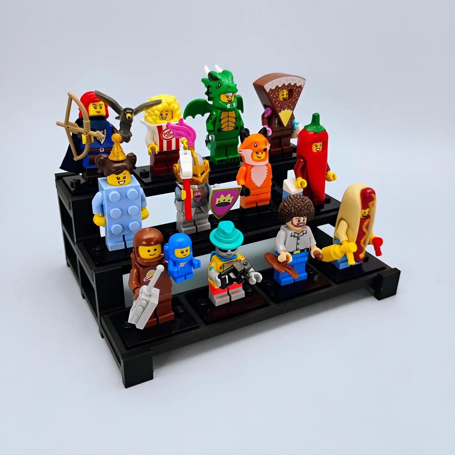 Compact tiered display stand for LEGO® minifigures with a colorful group of figures arranged in rows.