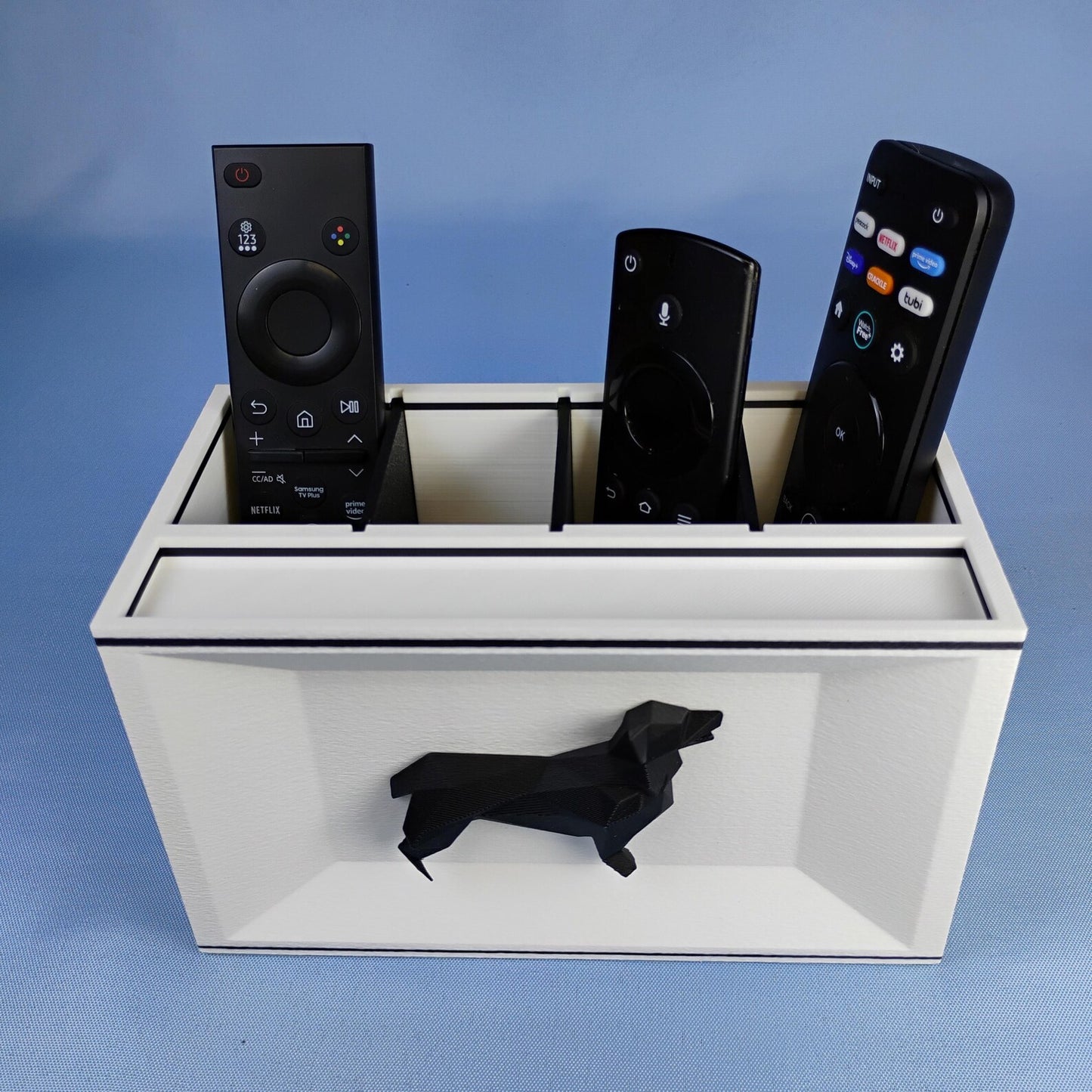 White Corgi remote holder with black dog detail photographed on a blue background