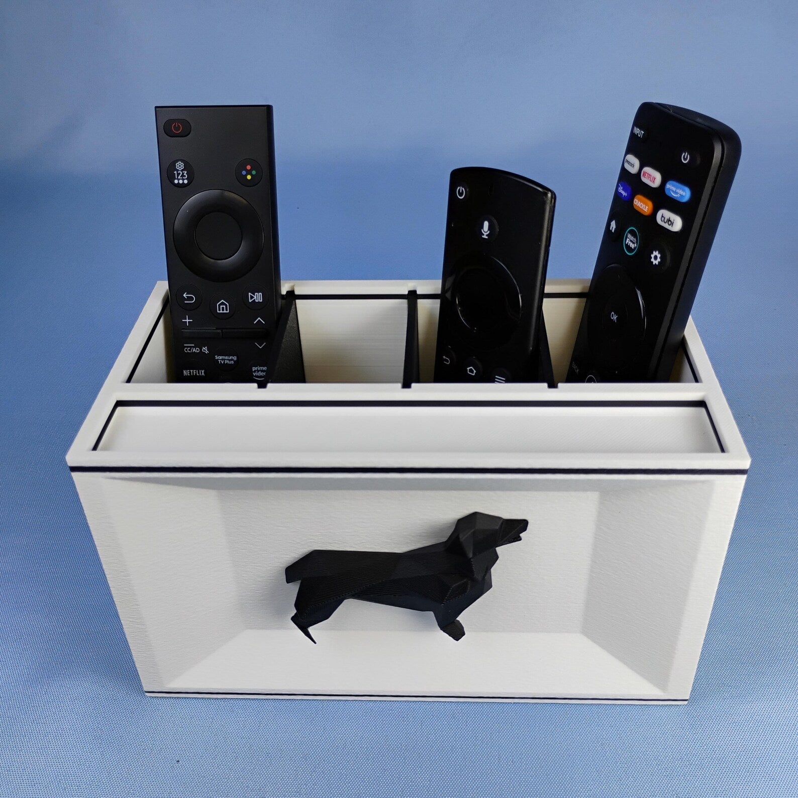 White Corgi remote holder with black dog detail photographed on a blue background