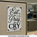 Eat Pray Cry funny office wall art displayed in a blurred office setting