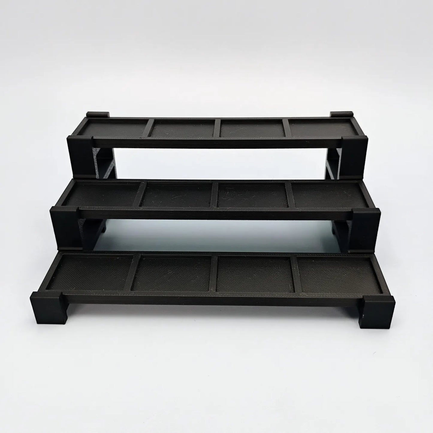 Empty black tiered display stand for LEGO® minifigures shown from the front on a clean white background.