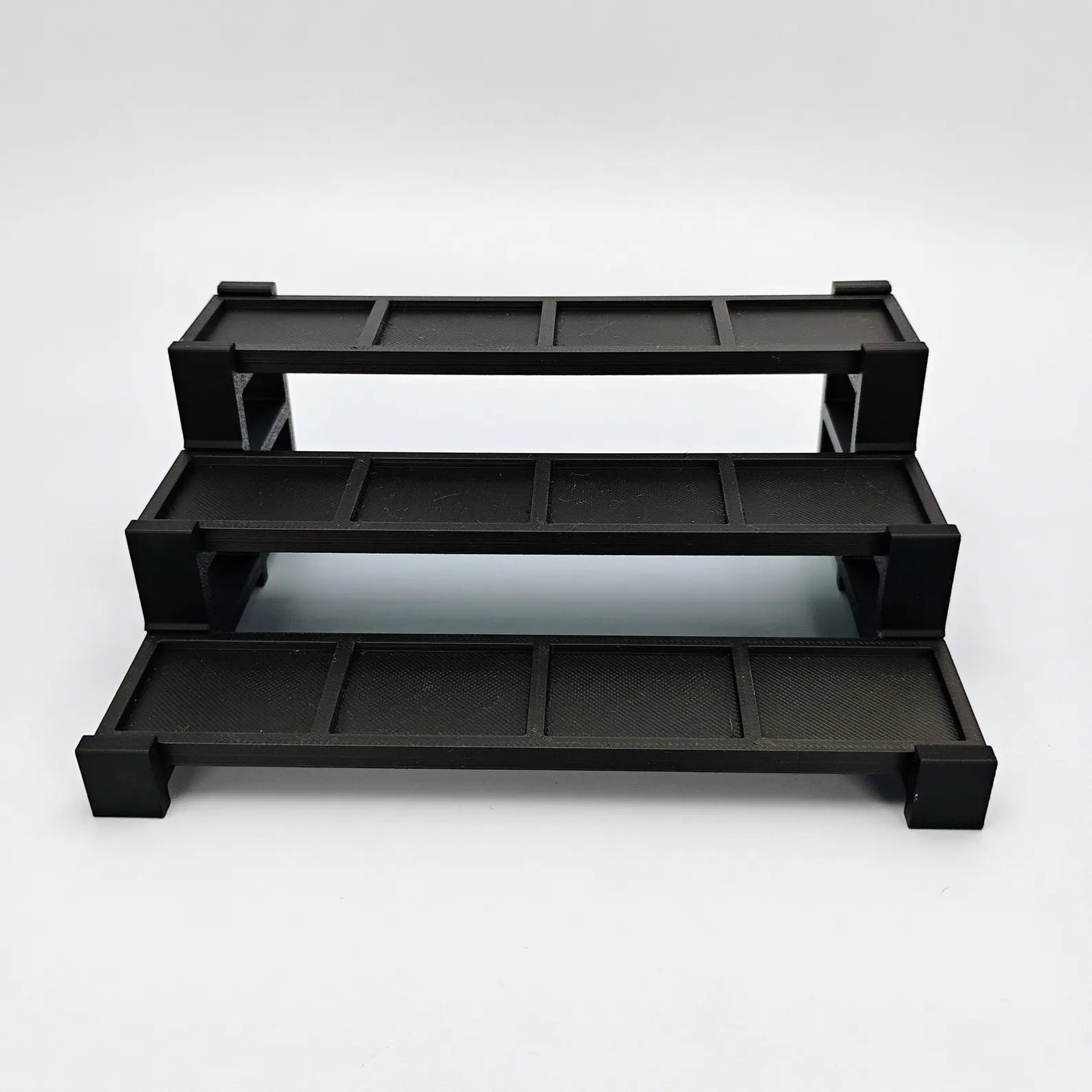 Empty black tiered display stand for LEGO® minifigures shown from the front on a clean white background.
