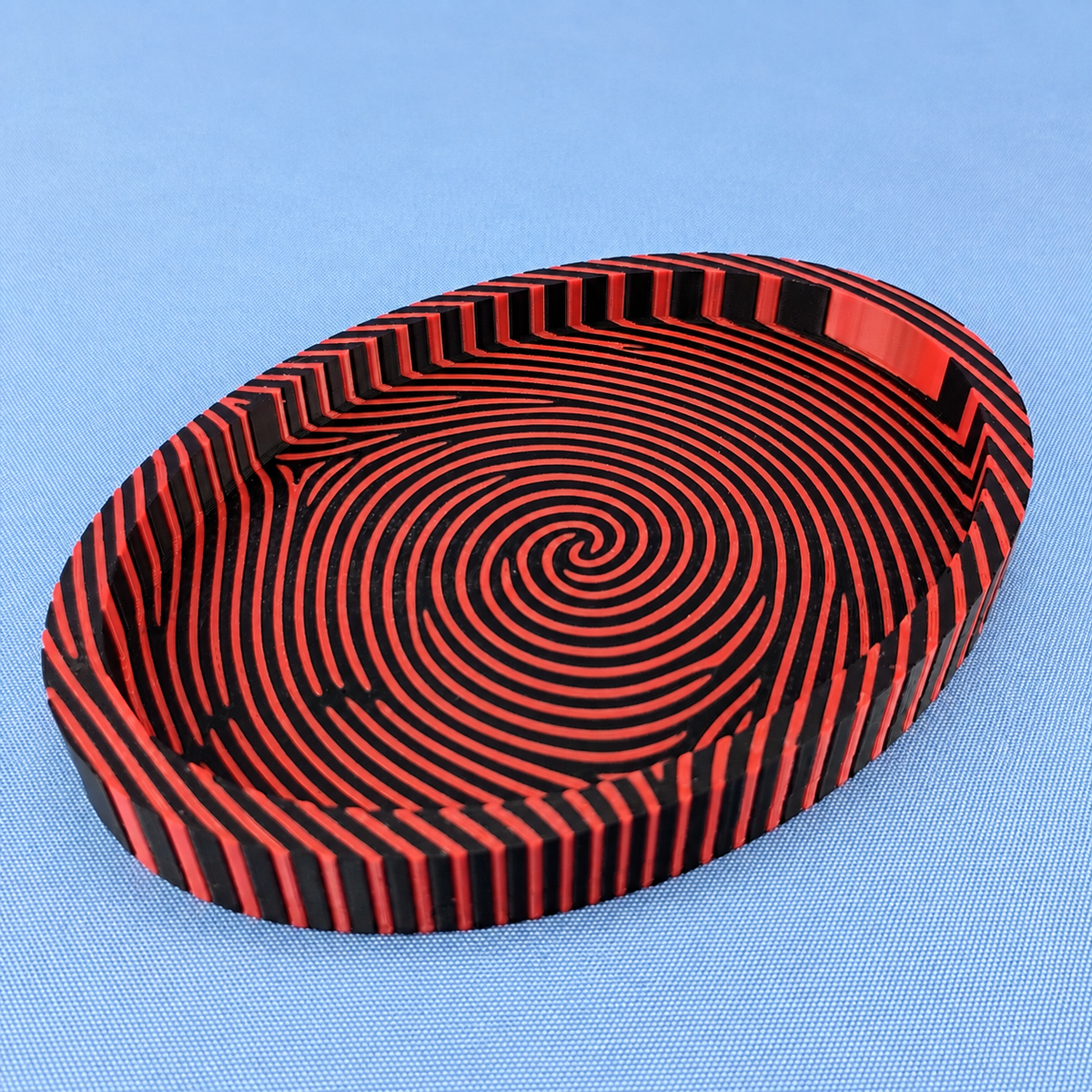 Black and red fingerprint catchall tray showing the bold striped fingerprint pattern across the base and sides.