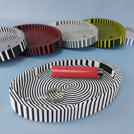 Fingerprint catchall trays in several color combinations, with a black and white tray holding a ring and red lighter.