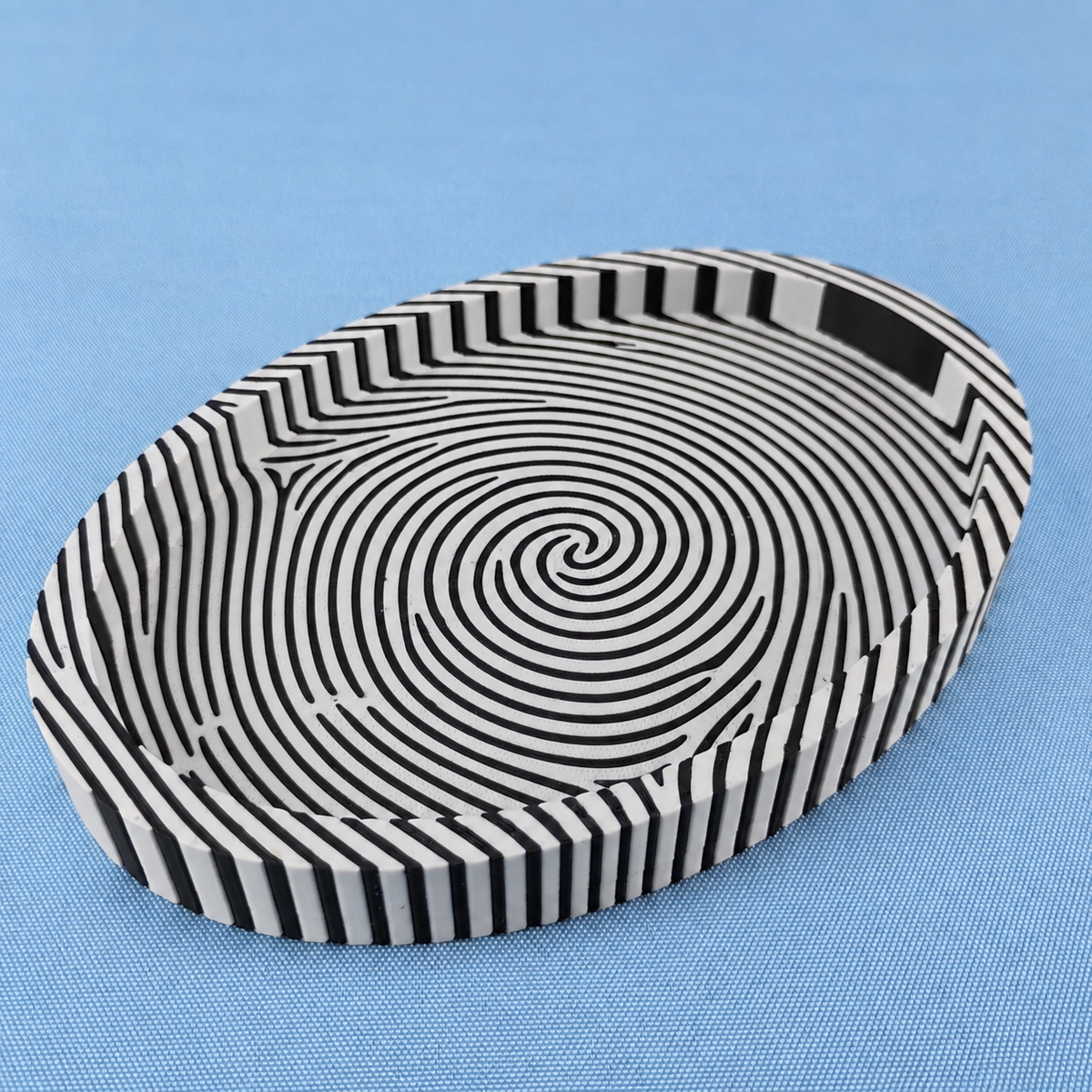White and black fingerprint catchall tray showing the bold striped fingerprint pattern across the base and sides.