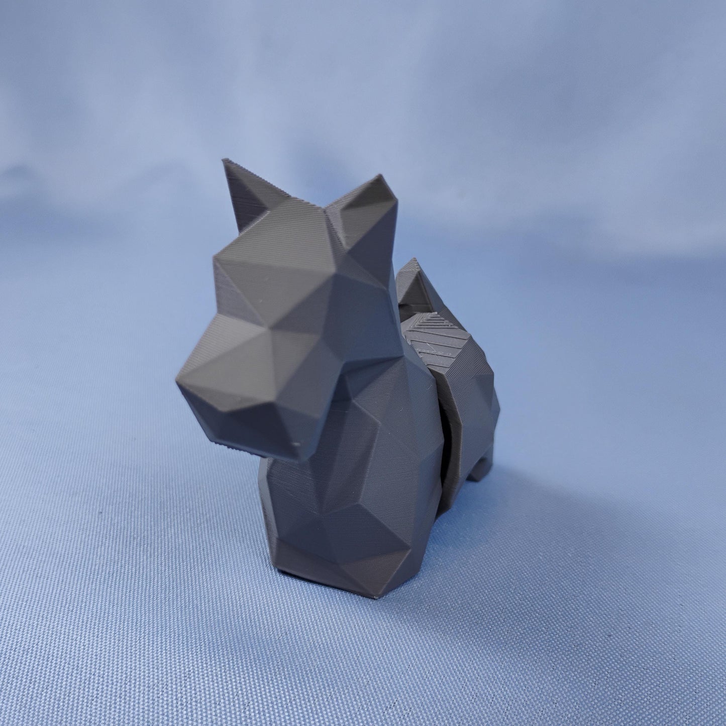 Front view of a gray flexi Scottish Terrier figurine with pointed ears, faceted low-poly surface, and compact display shape.