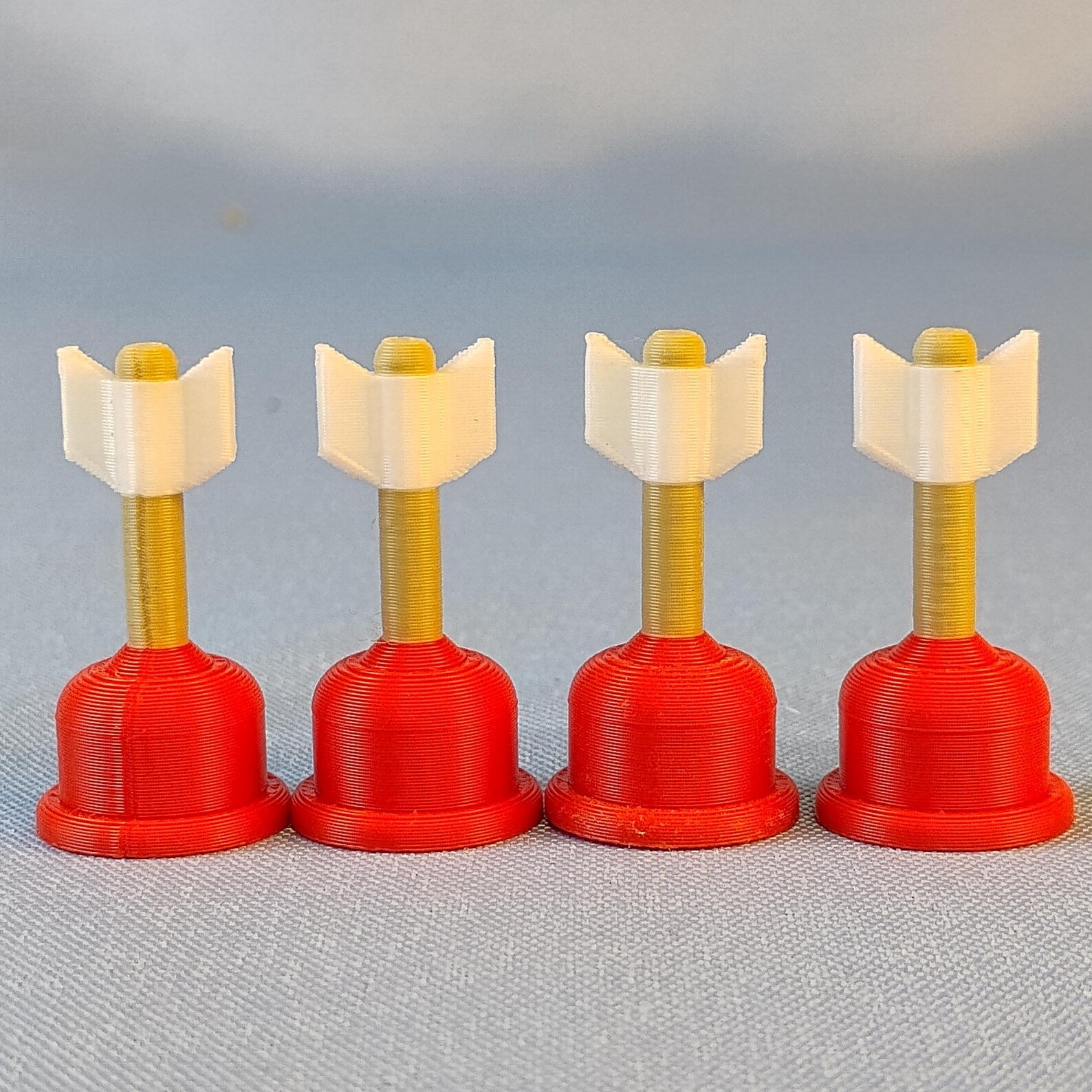 Four mini plunger Cupid arrow magnets lined up on a blue background for Valentine fridge decor and note holding.