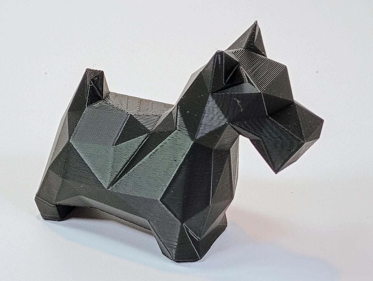 Black geometric Scottie dog decor figurine shown from a low side angle