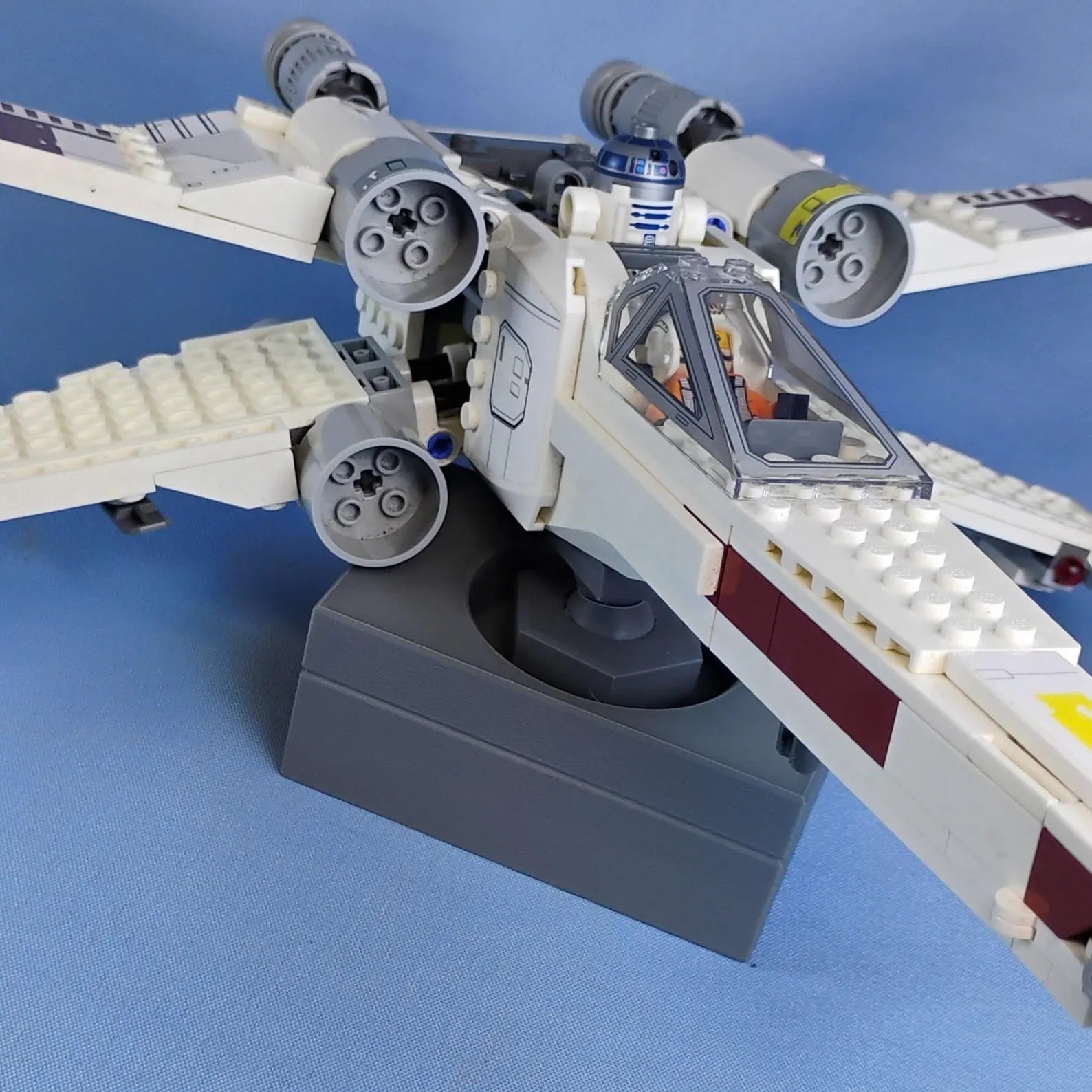 Close-up of gray adjustable display stand showing the ball joint mount and LEGO® ship connection point.