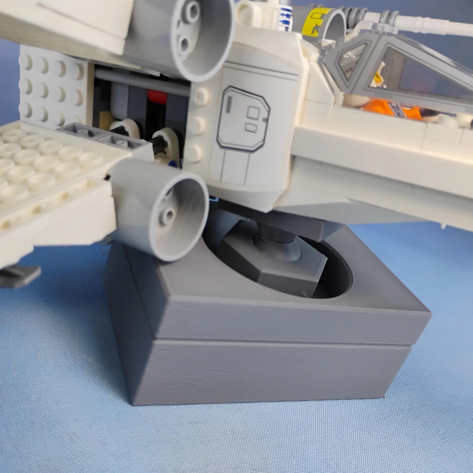 Close-up of gray adjustable display stand showing the ball joint mount and LEGO® ship connection point.