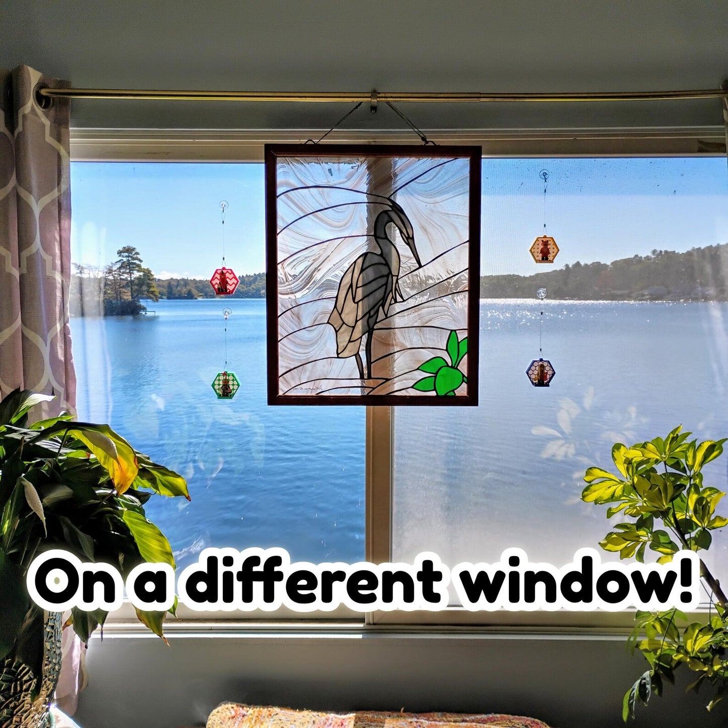 LEGO® minifigure displays hanging on a window with suction cups, shown with a bright outdoor view in the background.