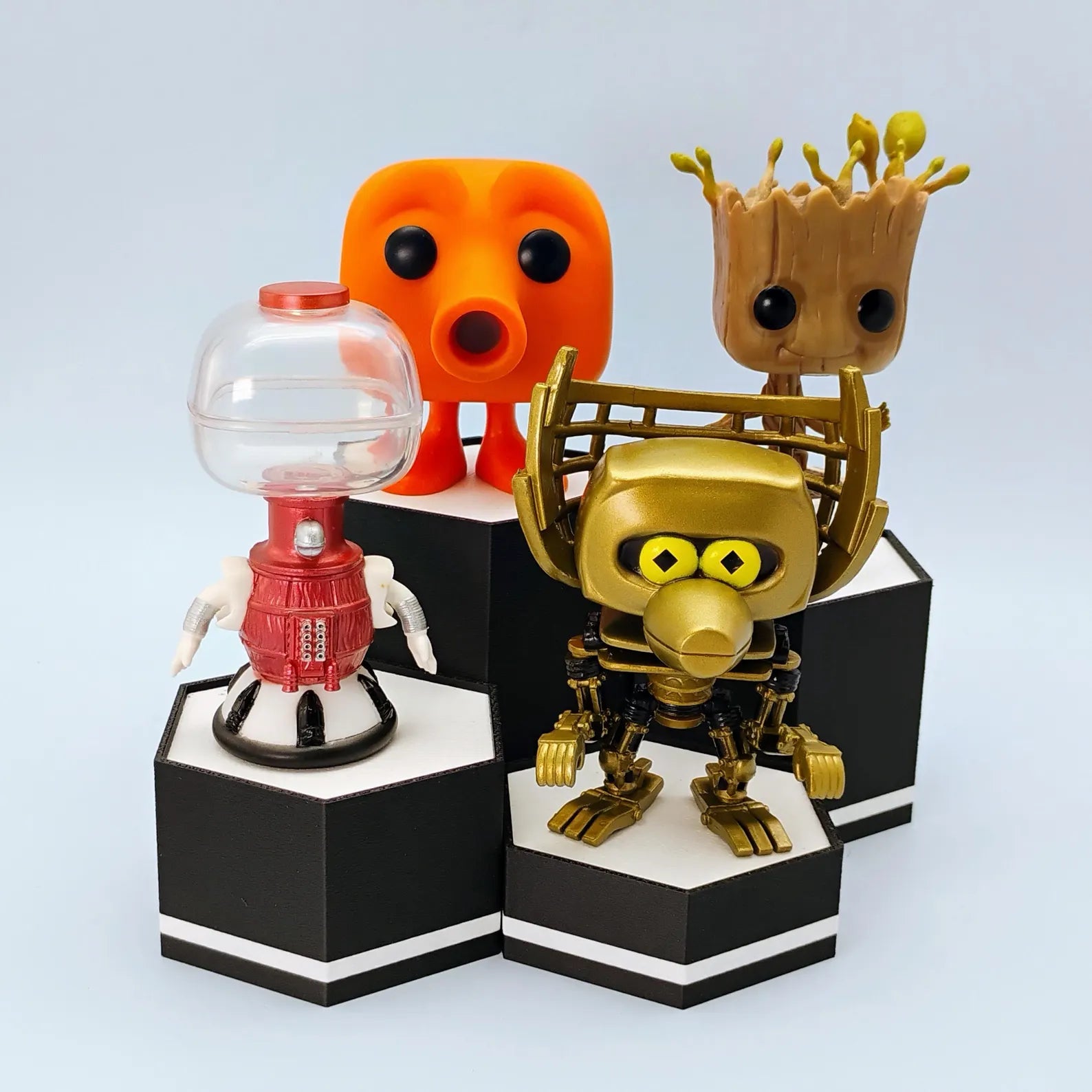 Black and white hex display stands shown with small collectible figures arranged at different heights for shelf or desk display.