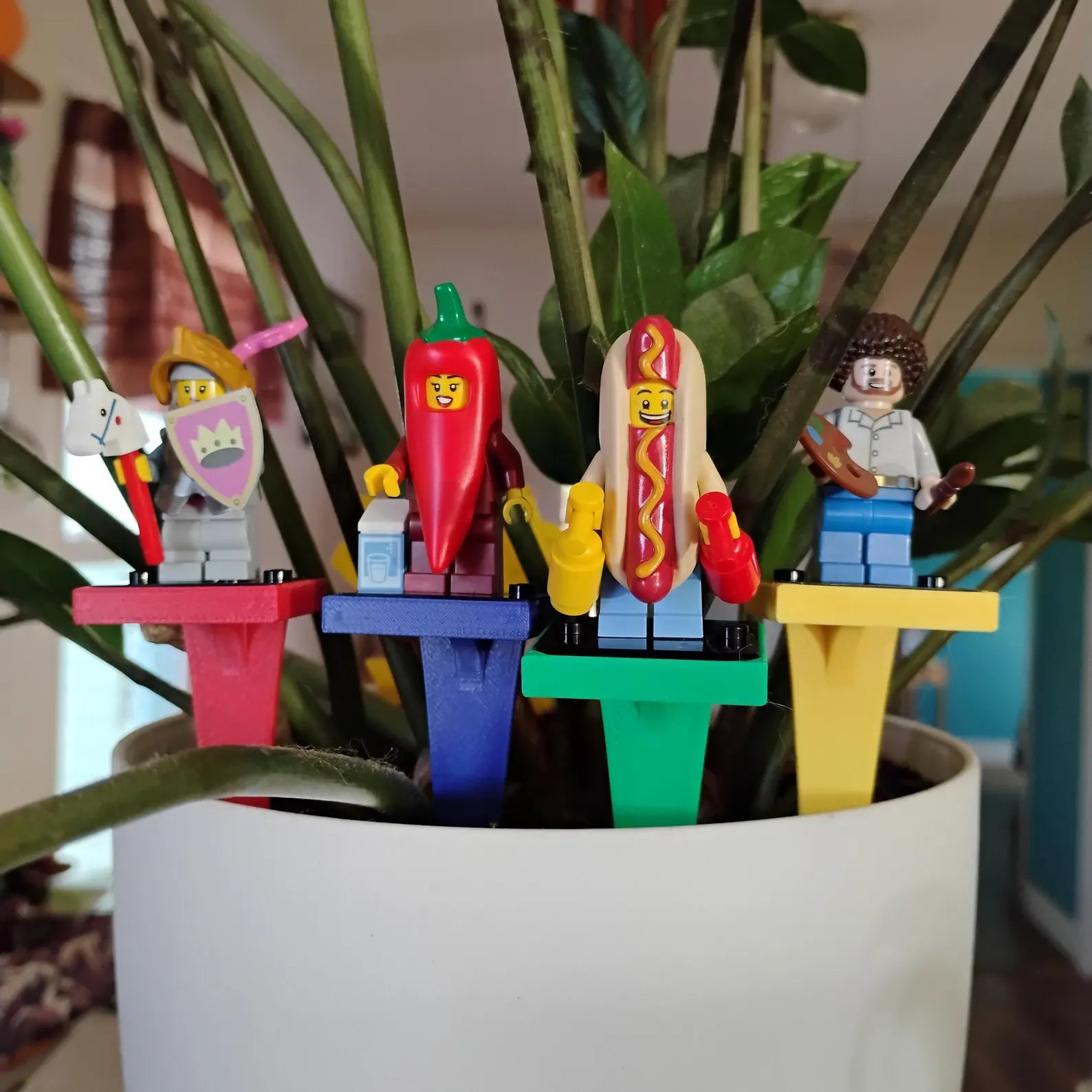 Colorful plant stakes holding LEGO® minifigures inside an indoor plant pot