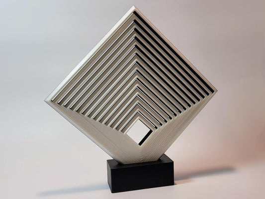 Comically large geometric fidget square displayed upright on a black stand