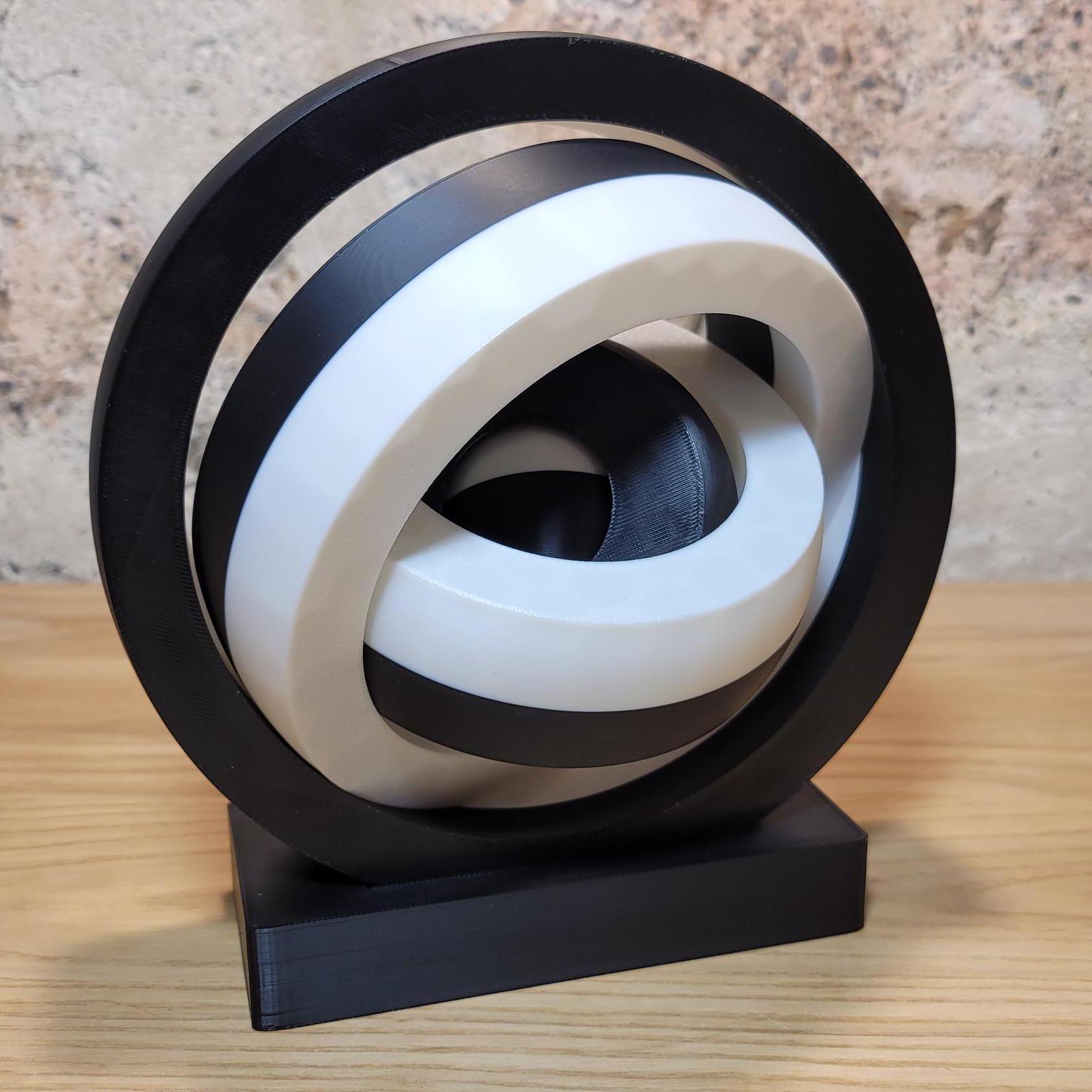 Large black and white kinetic fidget toy standing on a black base on a wooden tabletop