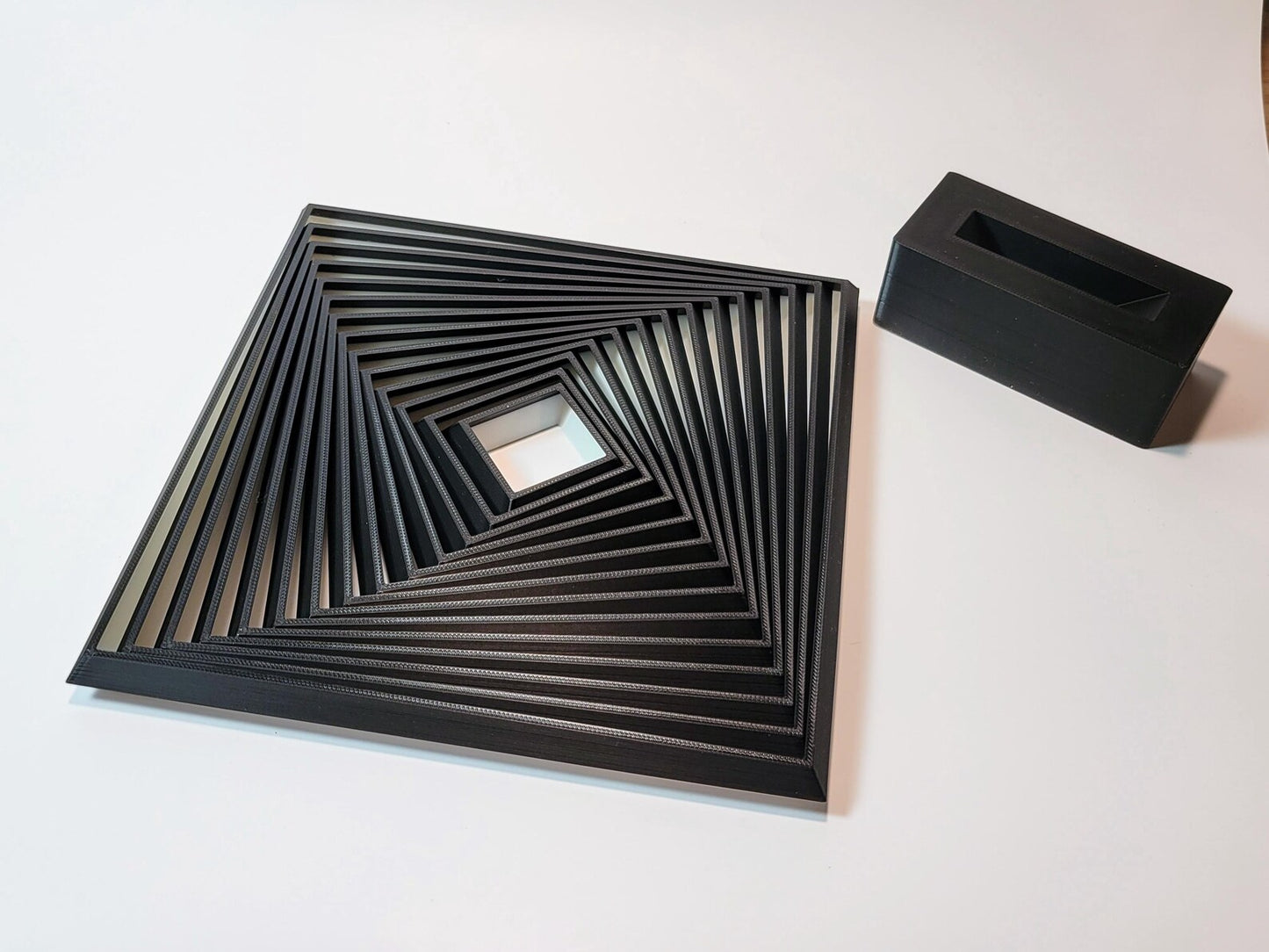Large layered geometric fidget toy shown at an angle with display stand nearby