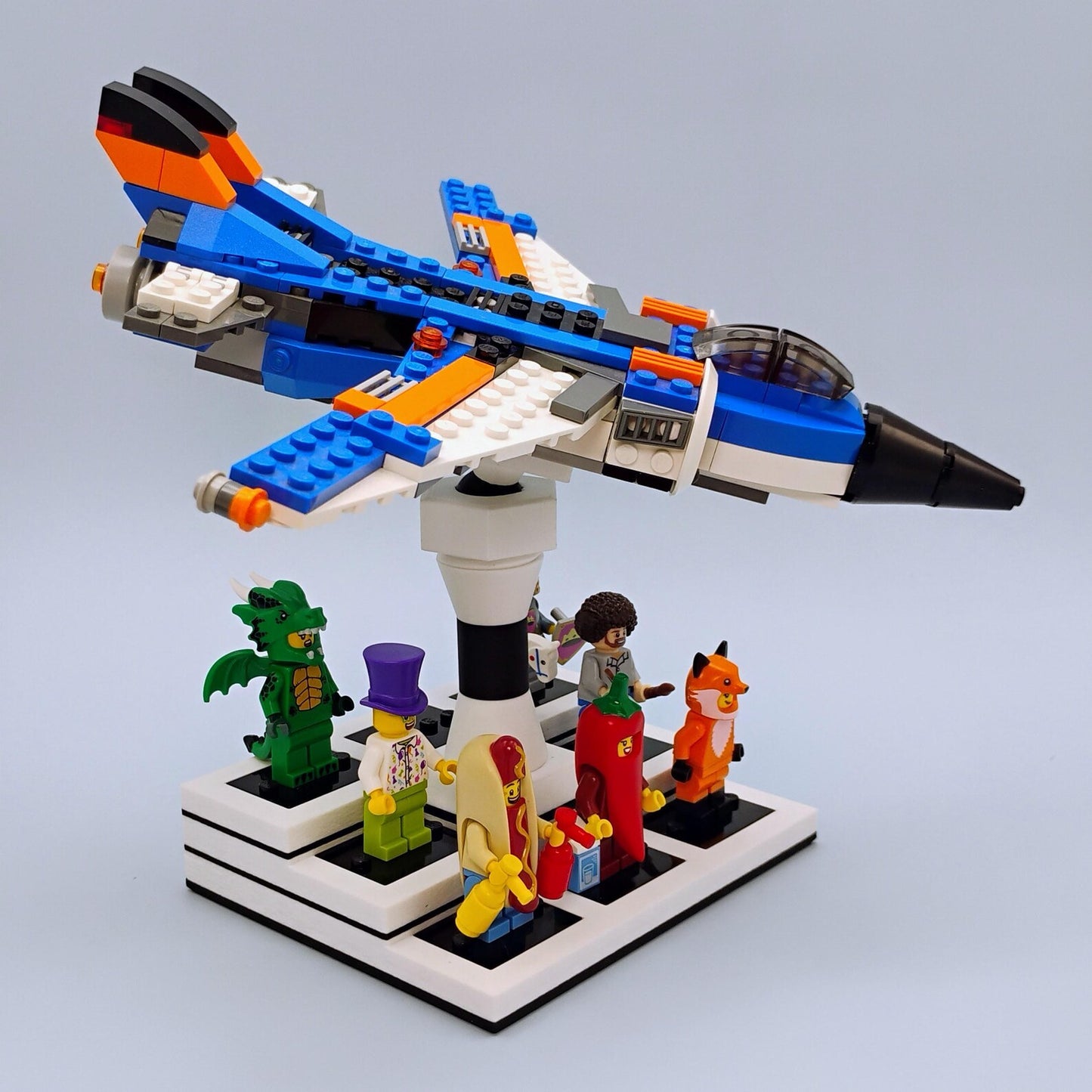 LEGO® airplane posed on a white adjustable display stand with minifigures arranged on the base for a clean shelf display.
