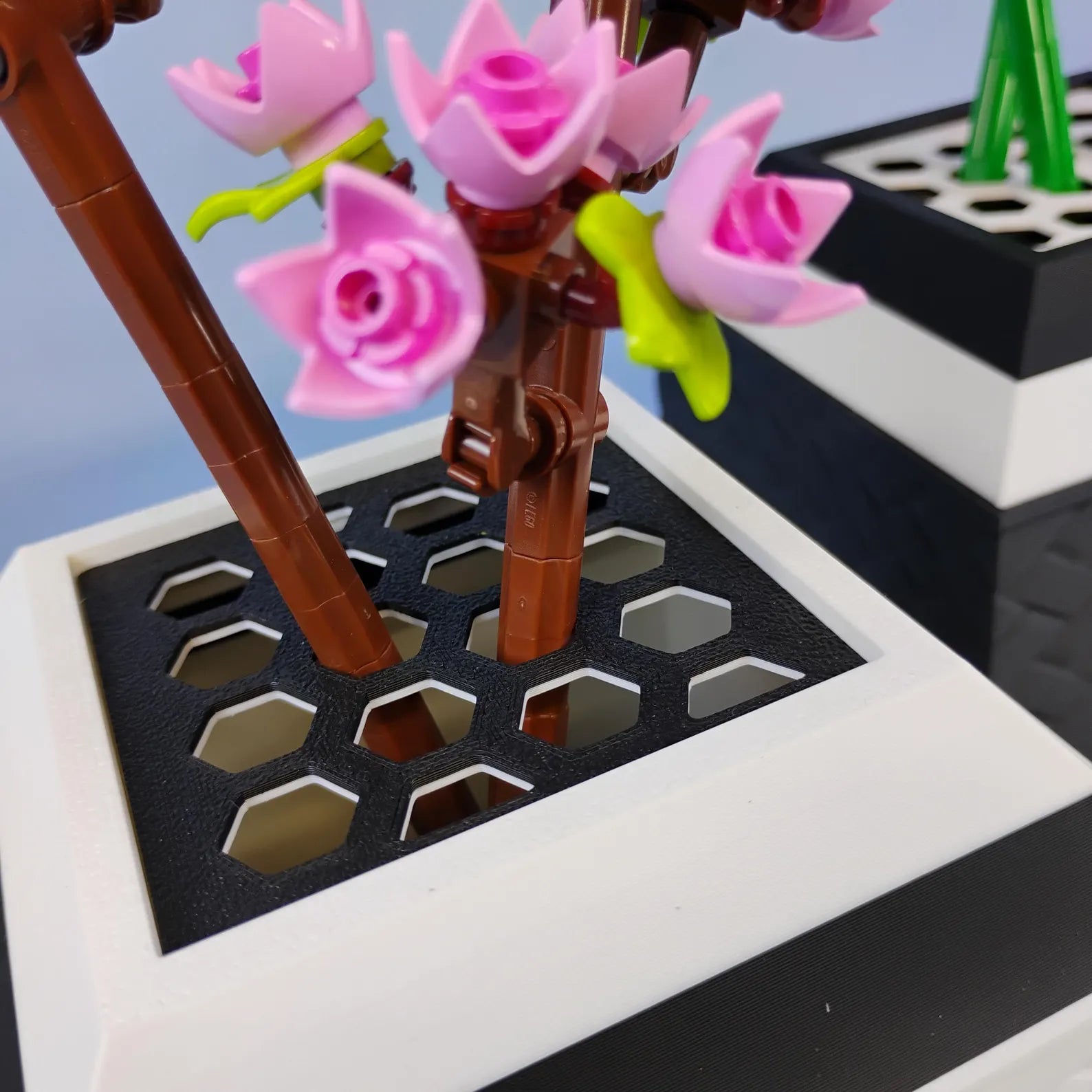 Close-up of LEGO® botanical stems placed into a removable grid insert inside the vase