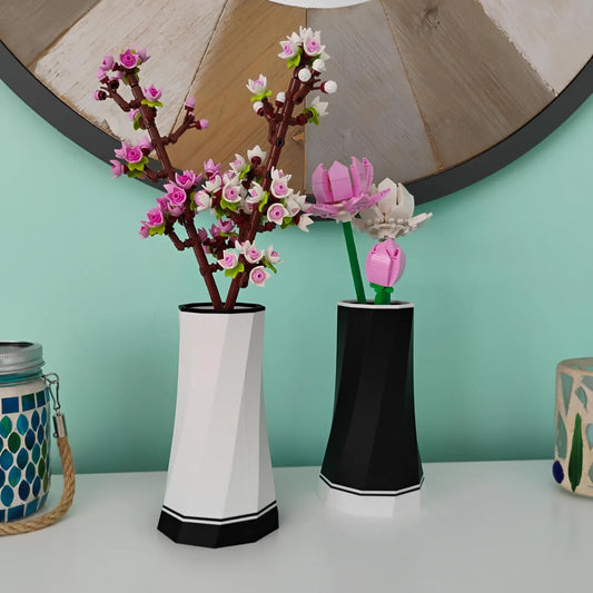 Black and white faceted vase displays holding LEGO® Botanical flower stems on a desk shelf, shown as modern home decor for flower bouquet builds.