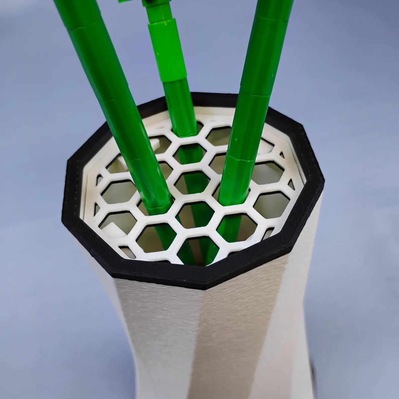 Close-up of the removable honeycomb stem insert inside the vase, holding green LEGO® Botanical flower stems upright and organized.