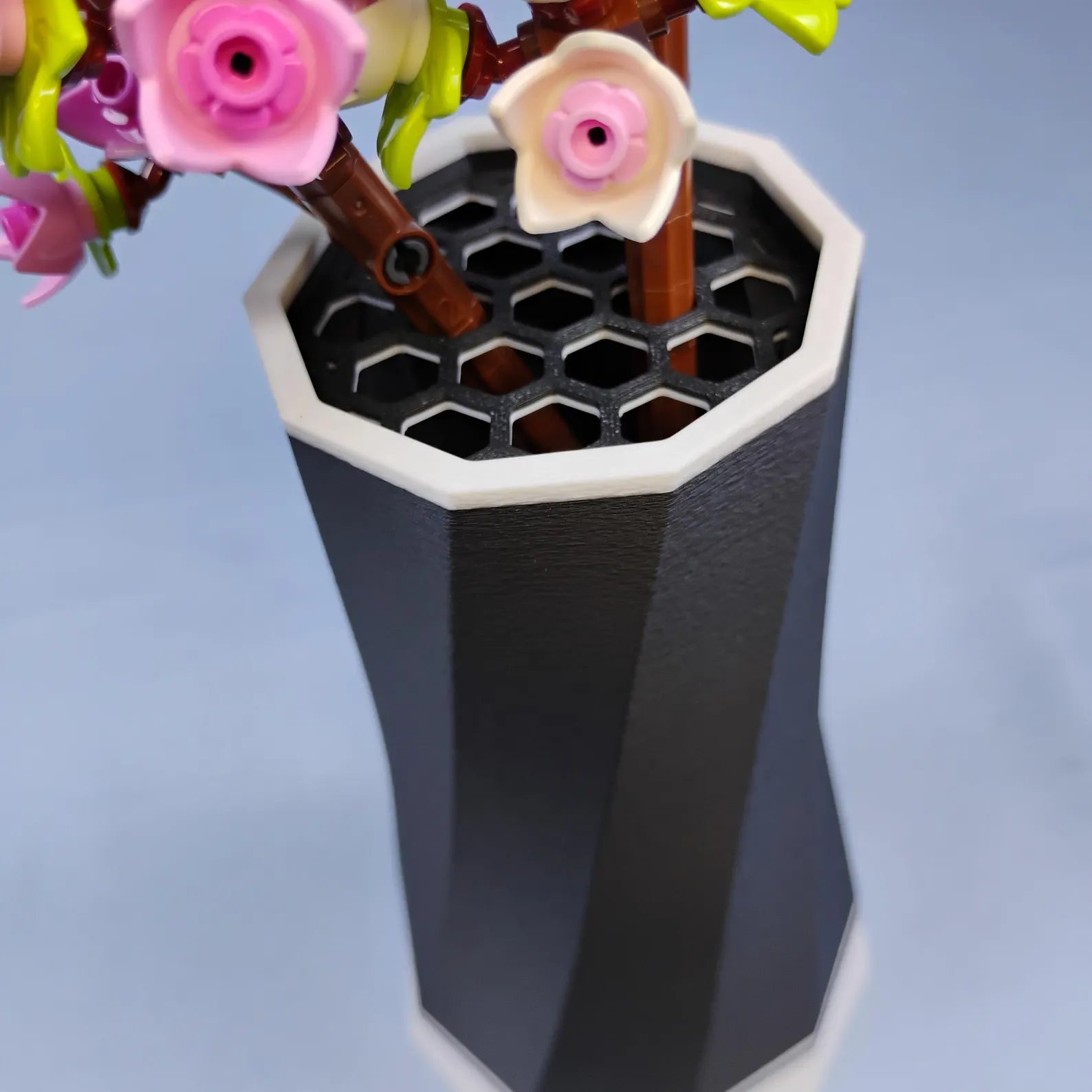 Close-up of LEGO® Botanical flowers placed into the vase’s top grid insert, designed to keep flower stems straight and secure.