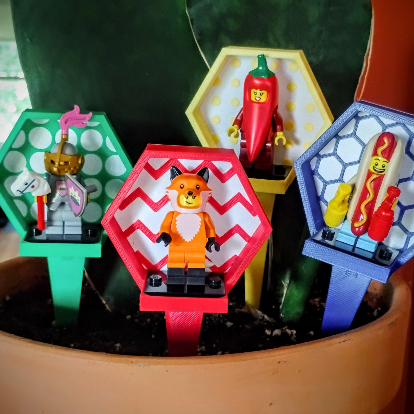 Several colorful LEGO® minifigure garden stake displays arranged together in a potted plant with assorted minifigures.